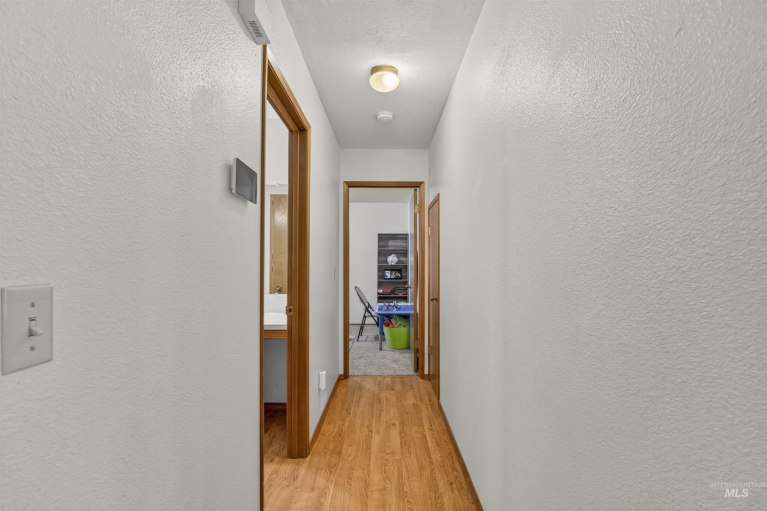 Hall featuring light wood-type flooring and a textured wall