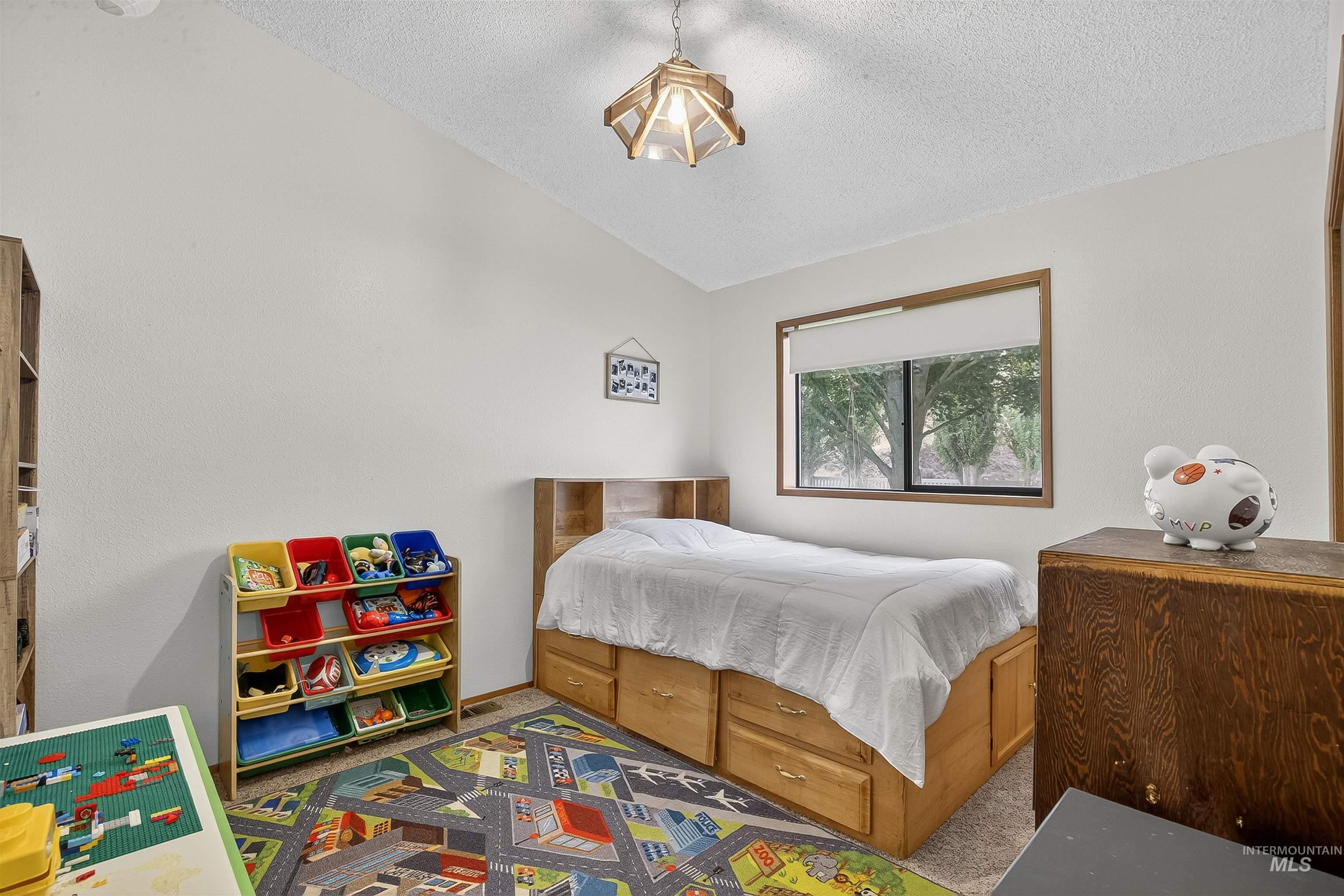 Carpeted bedroom featuring vaulted ceiling and a textured ceiling