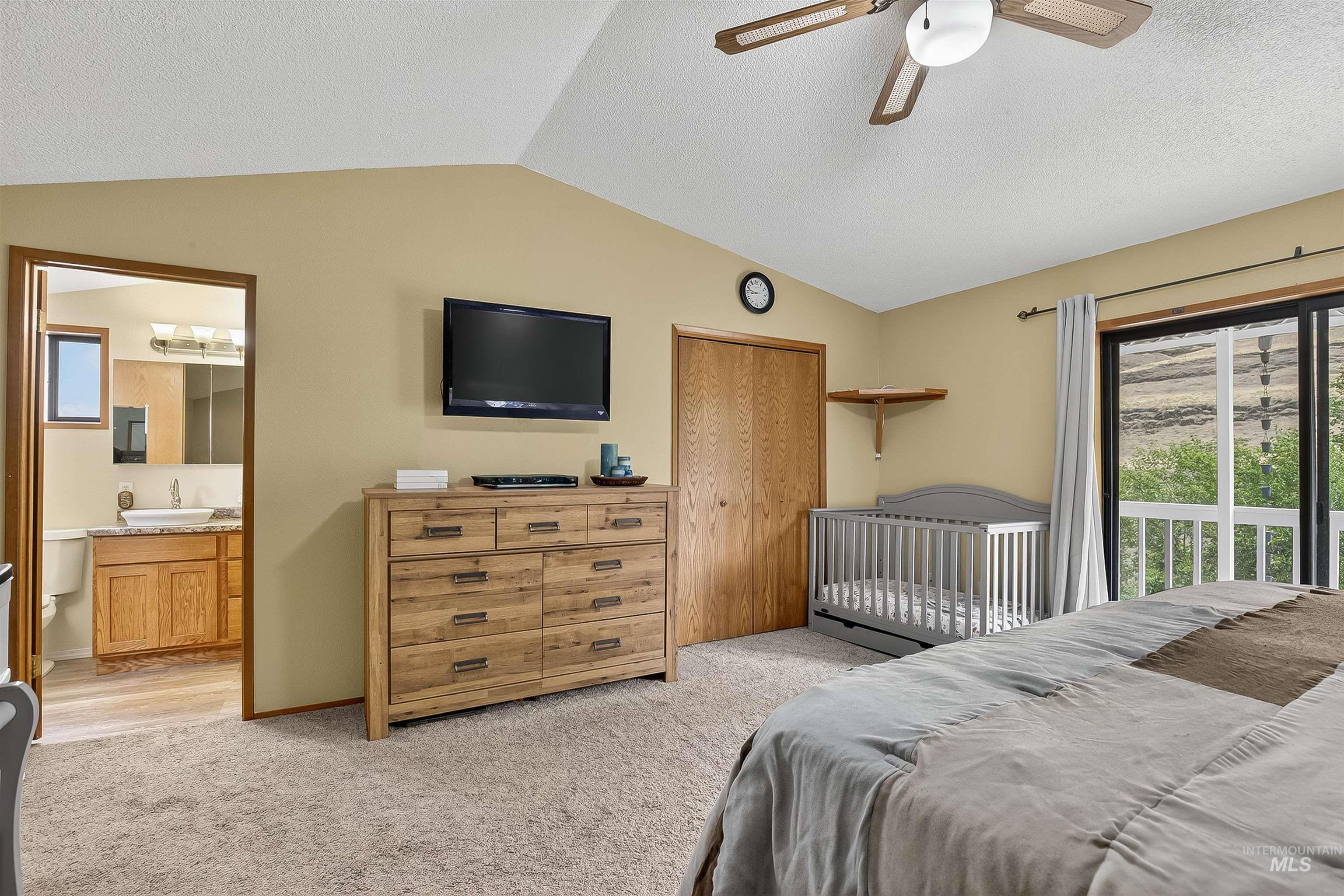 Bedroom with a closet, vaulted ceiling, access to exterior, light carpet, and a textured ceiling