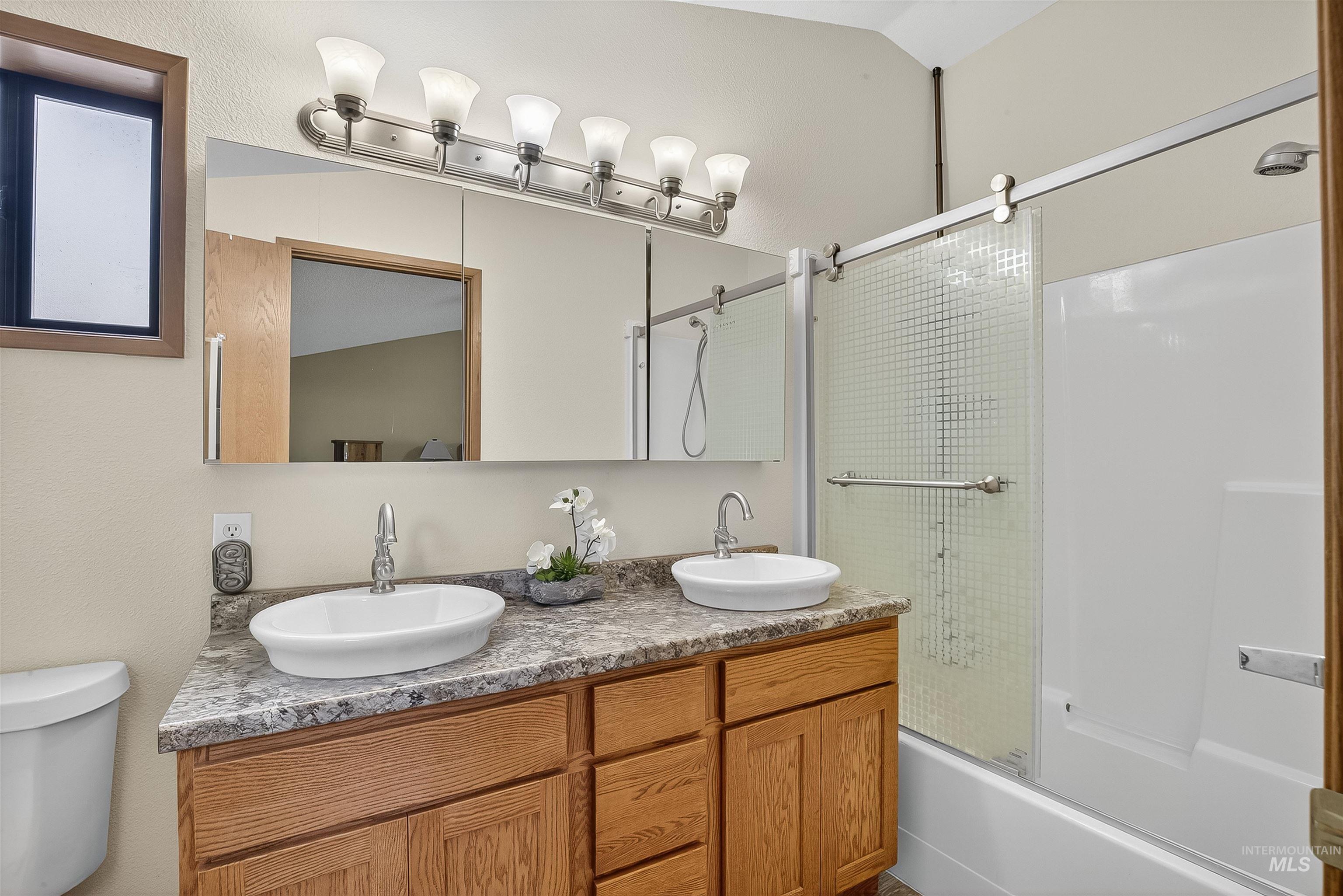 Full bathroom with combined bath / shower with glass door and double vanity