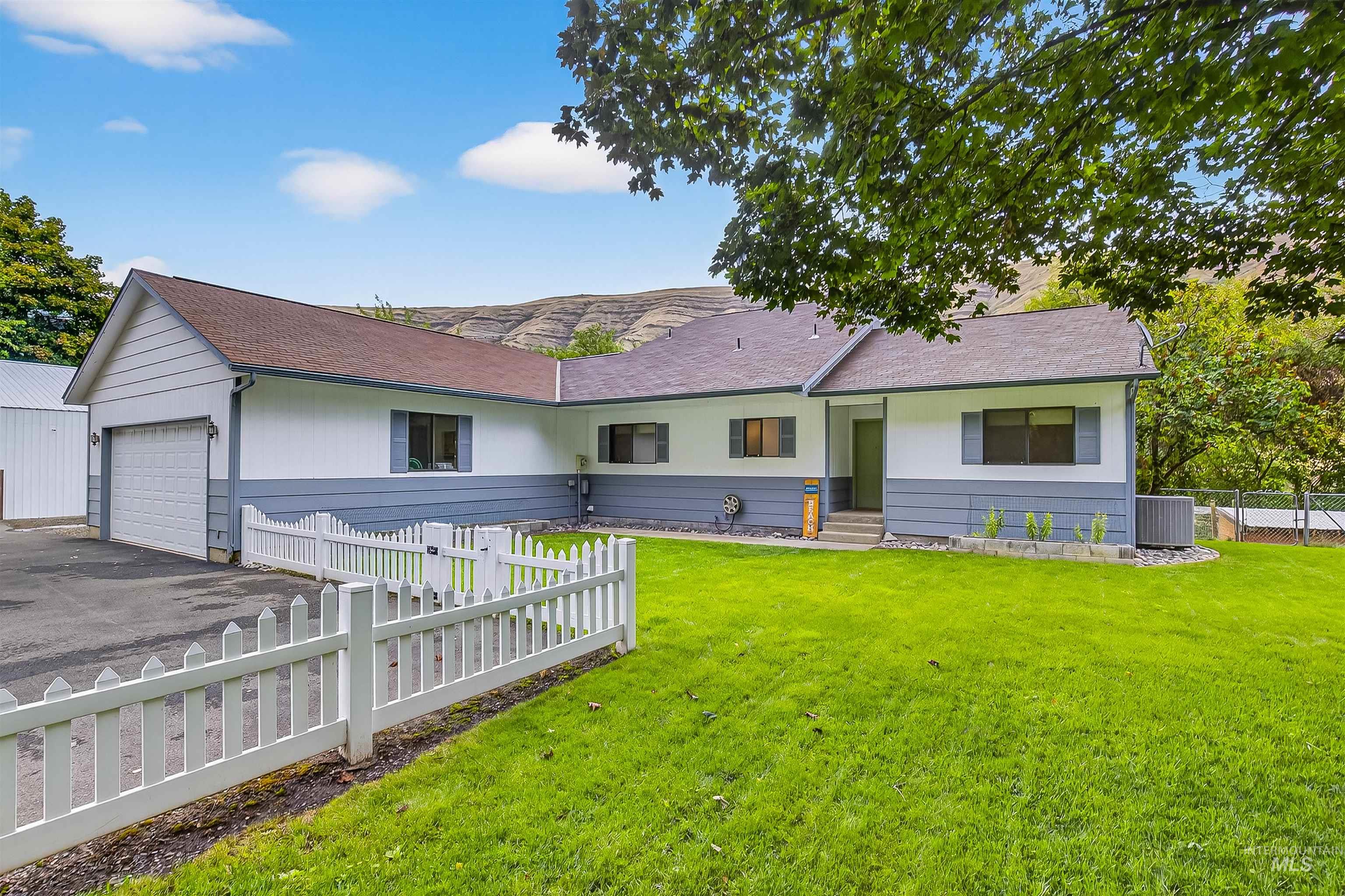 Rear view of property featuring a shingled roof, driveway, and a garage