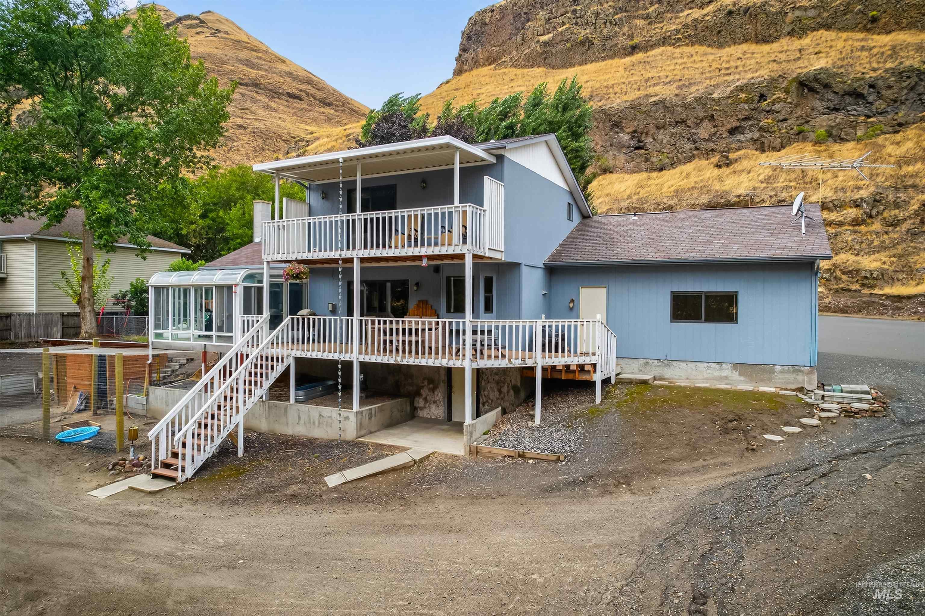 Rear view of property featuring a balcony, stairway, a deck with mountain view, and a shingled roof