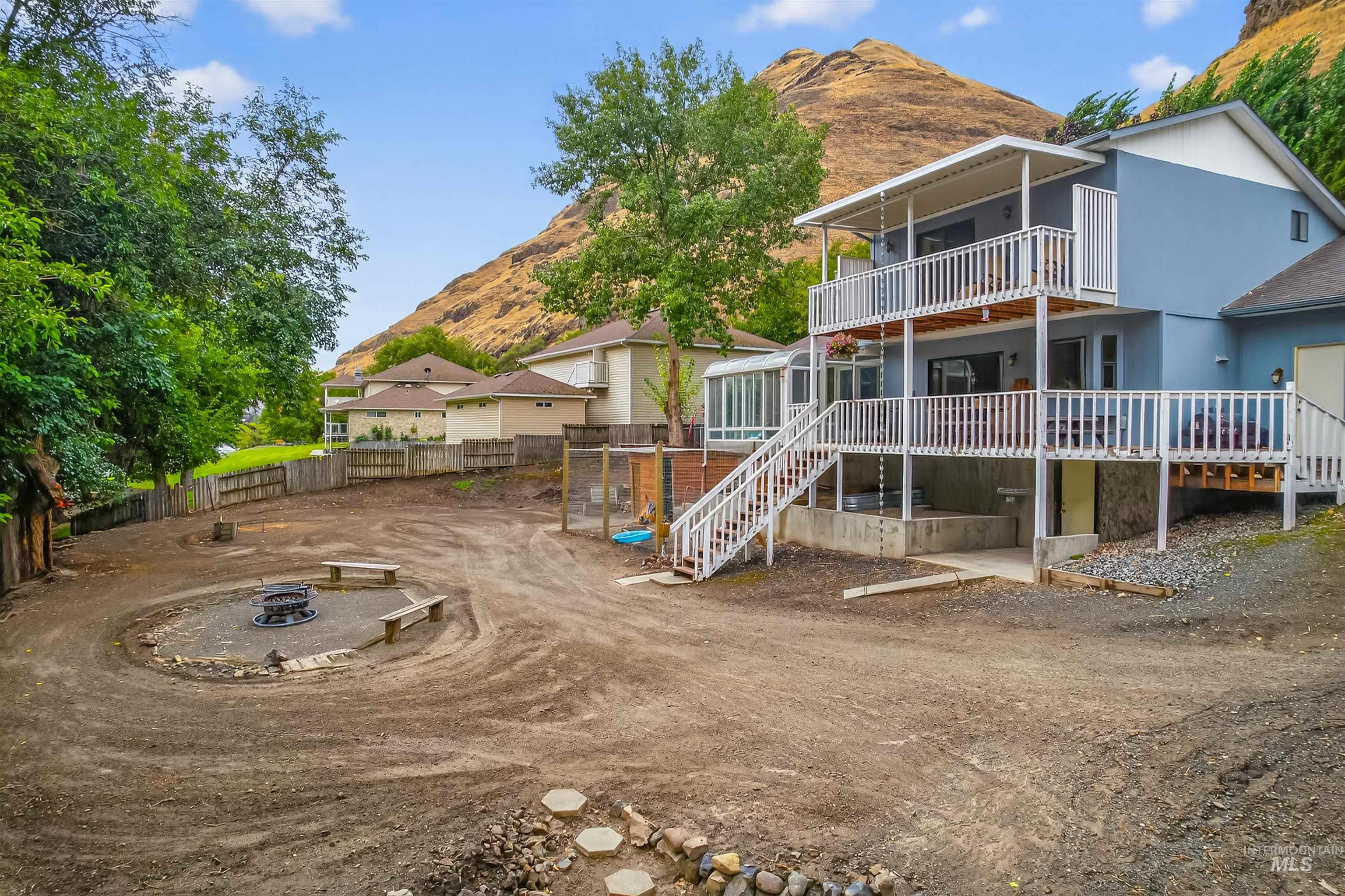 Back of house with a balcony, a patio area, stairs, a fire pit, and a deck with mountain view