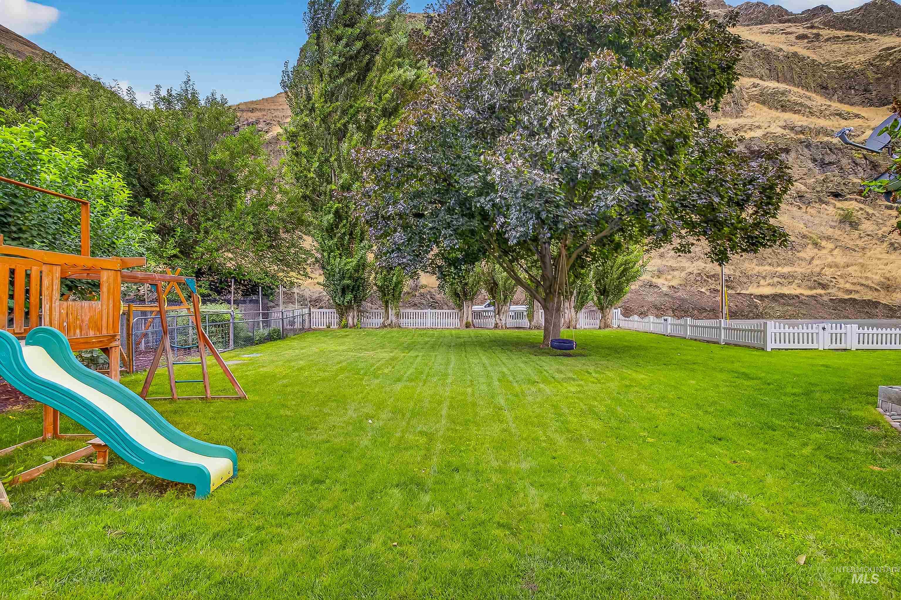 Fenced backyard featuring a playground and a mountain view