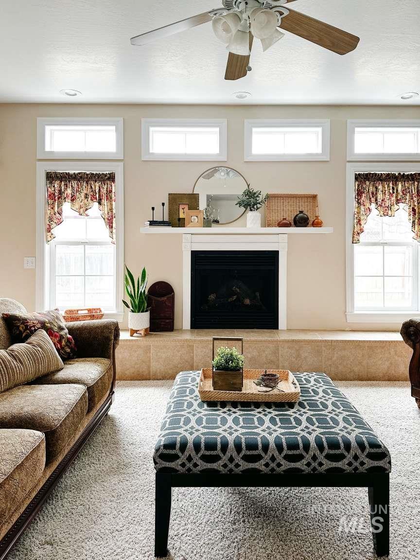Living area with a ceiling fan, a fireplace with raised hearth, and a textured ceiling
