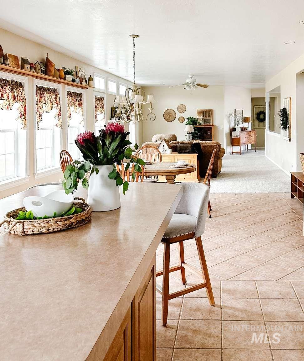 Dining area with ceiling fan, light tile patterned flooring, and light carpet