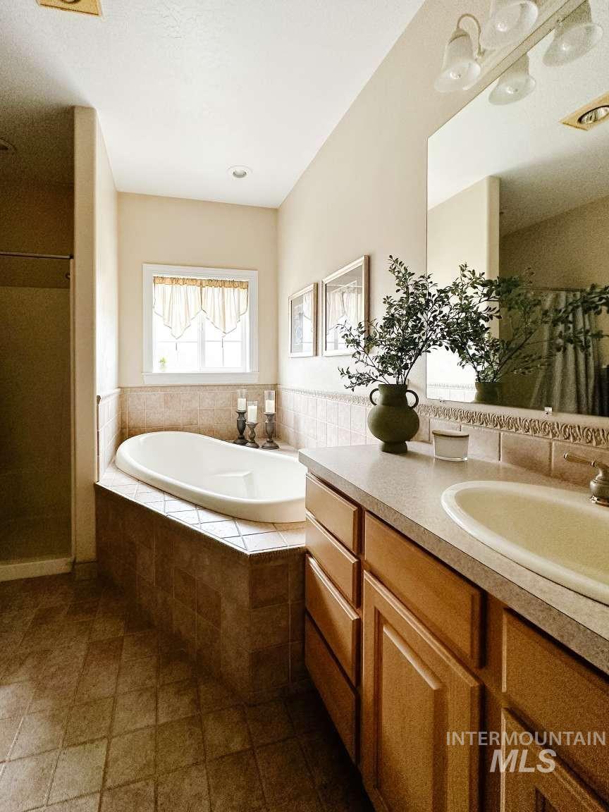 Full bath featuring a shower stall, a garden tub, and vanity