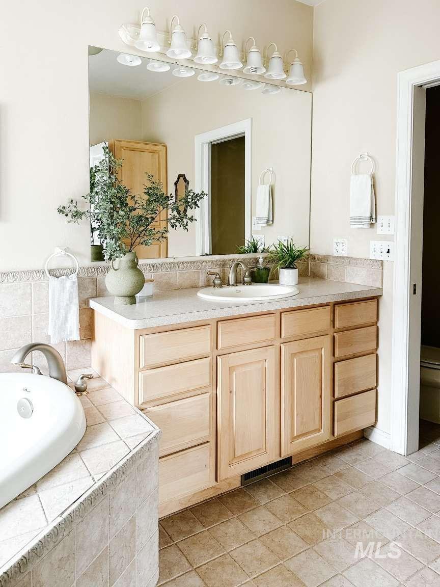 Bathroom with vanity, a bath, and light tile patterned floors
