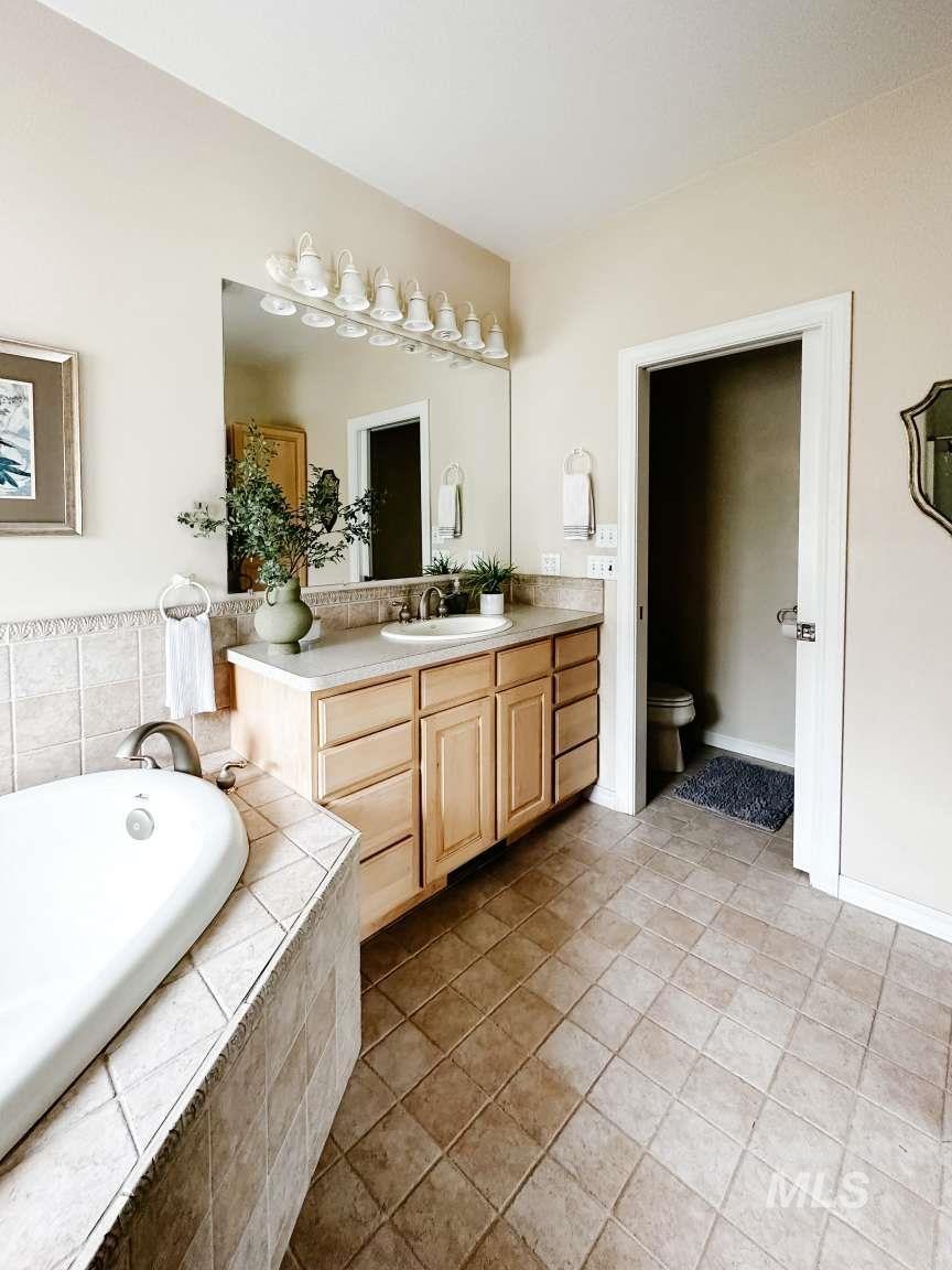 Full bath featuring vanity, a bath, and light tile patterned floors