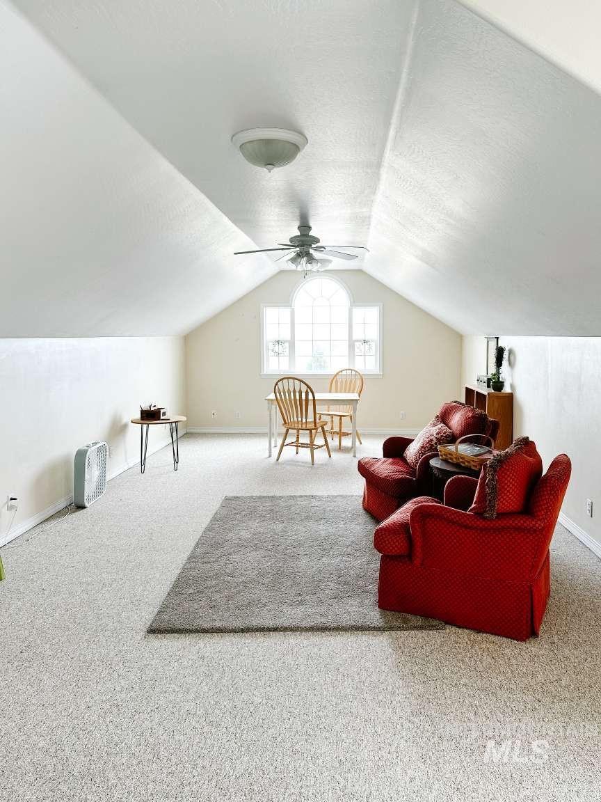 Bonus room featuring carpet flooring, lofted ceiling, a textured ceiling, and a ceiling fan
