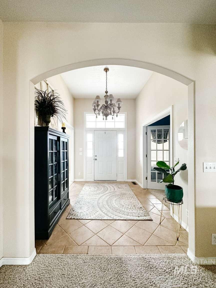 Entryway featuring arched walkways, light tile patterned floors, and a chandelier
