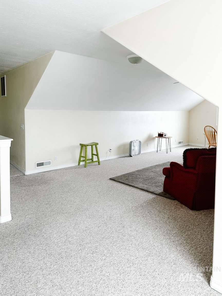 Bonus room featuring vaulted ceiling and light colored carpet