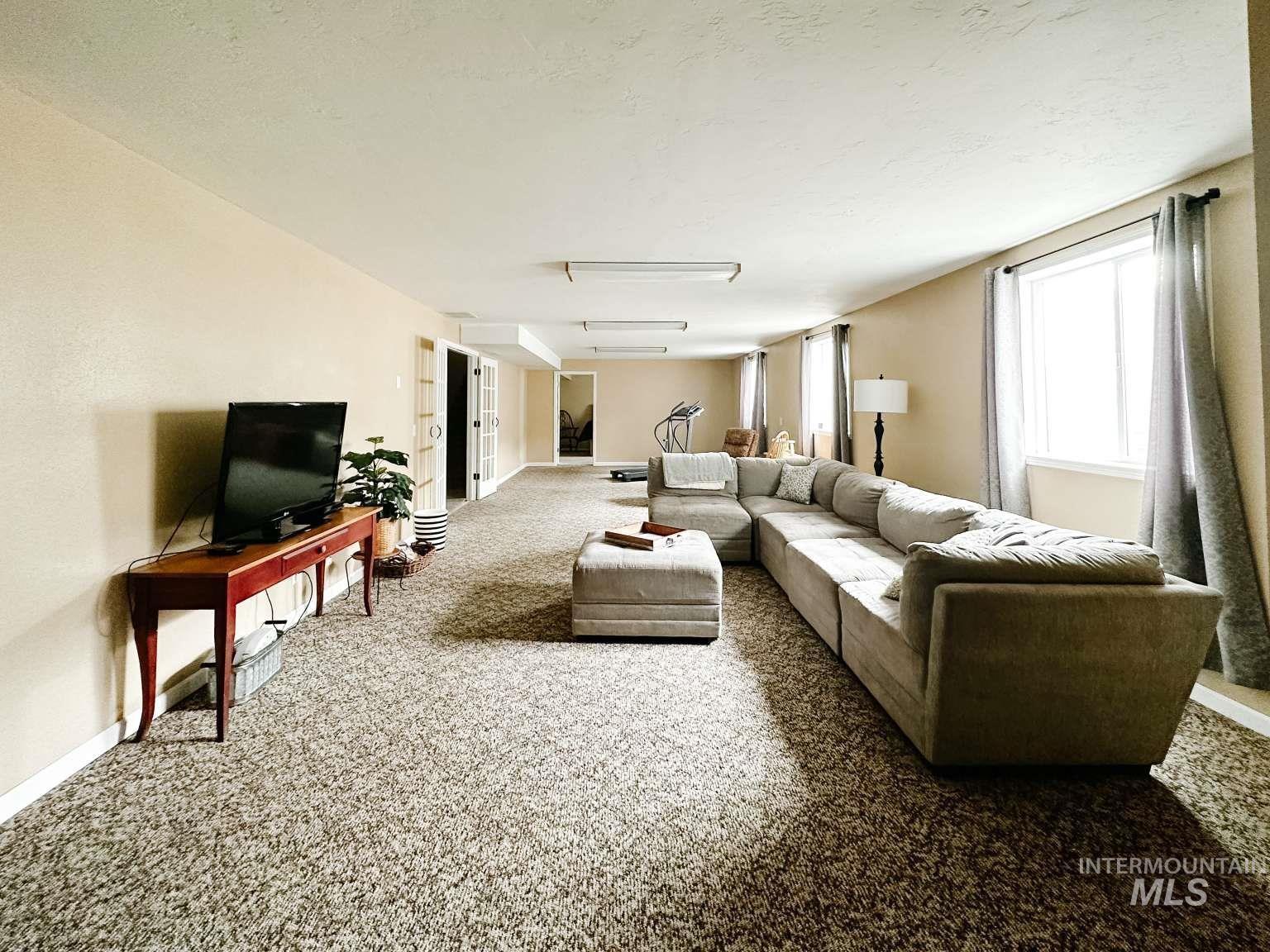 Carpeted living area with baseboards and a textured ceiling
