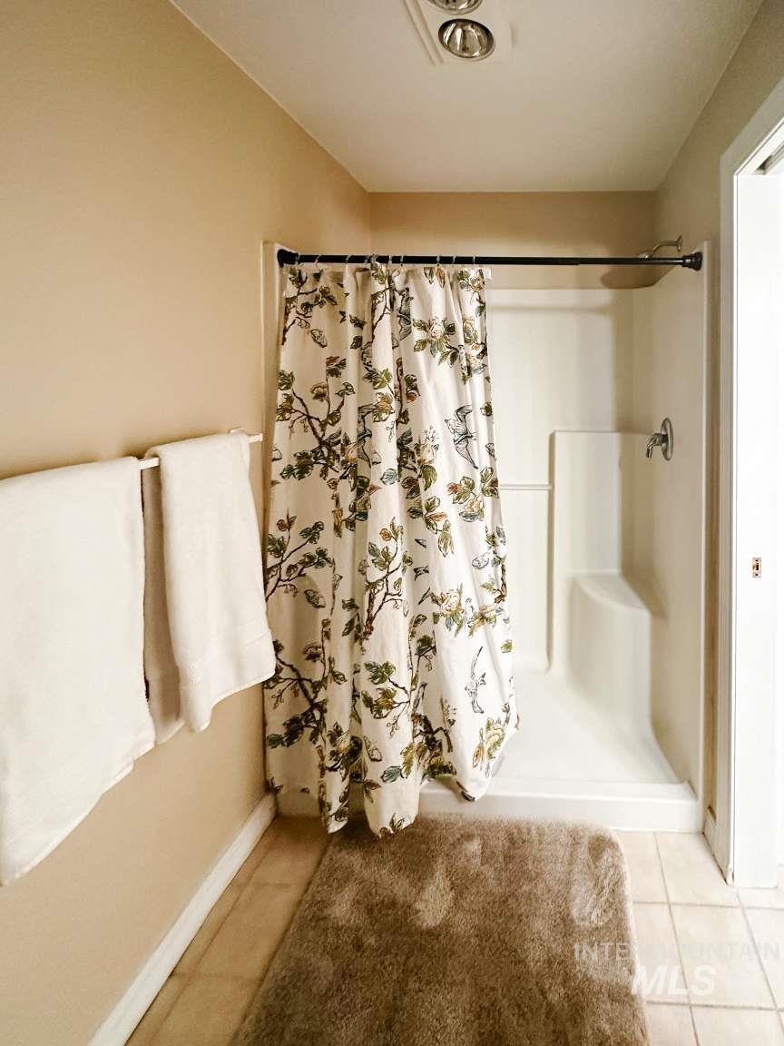 Full bathroom with light tile patterned floors and a shower stall