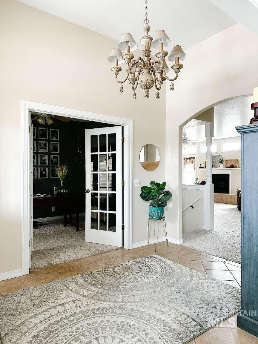 Doorway to outside with carpet, tile patterned flooring, arched walkways, a fireplace, and a chandelier