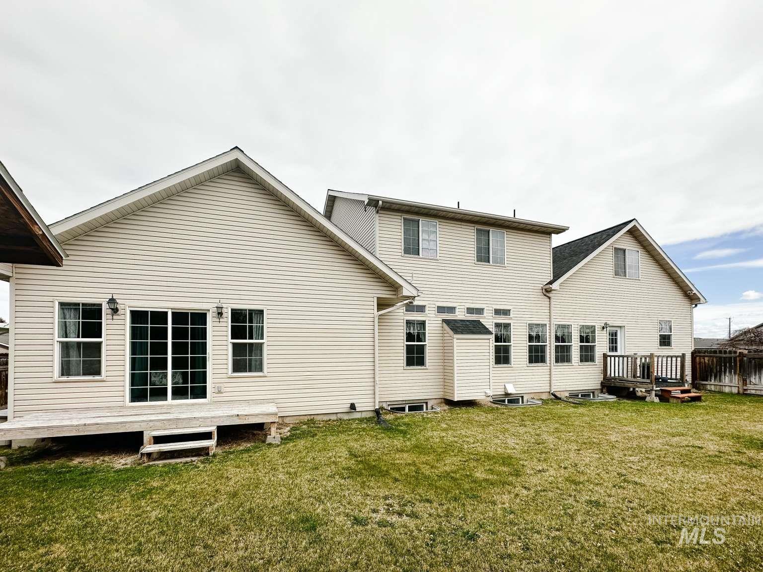 Rear view of property with a wooden deck and a lawn