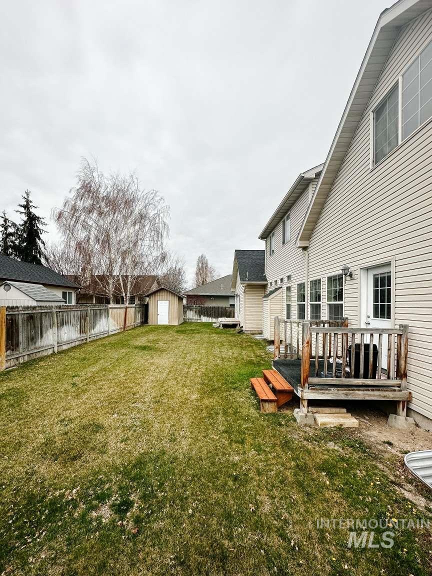 Fenced backyard featuring a storage shed and a wooden deck