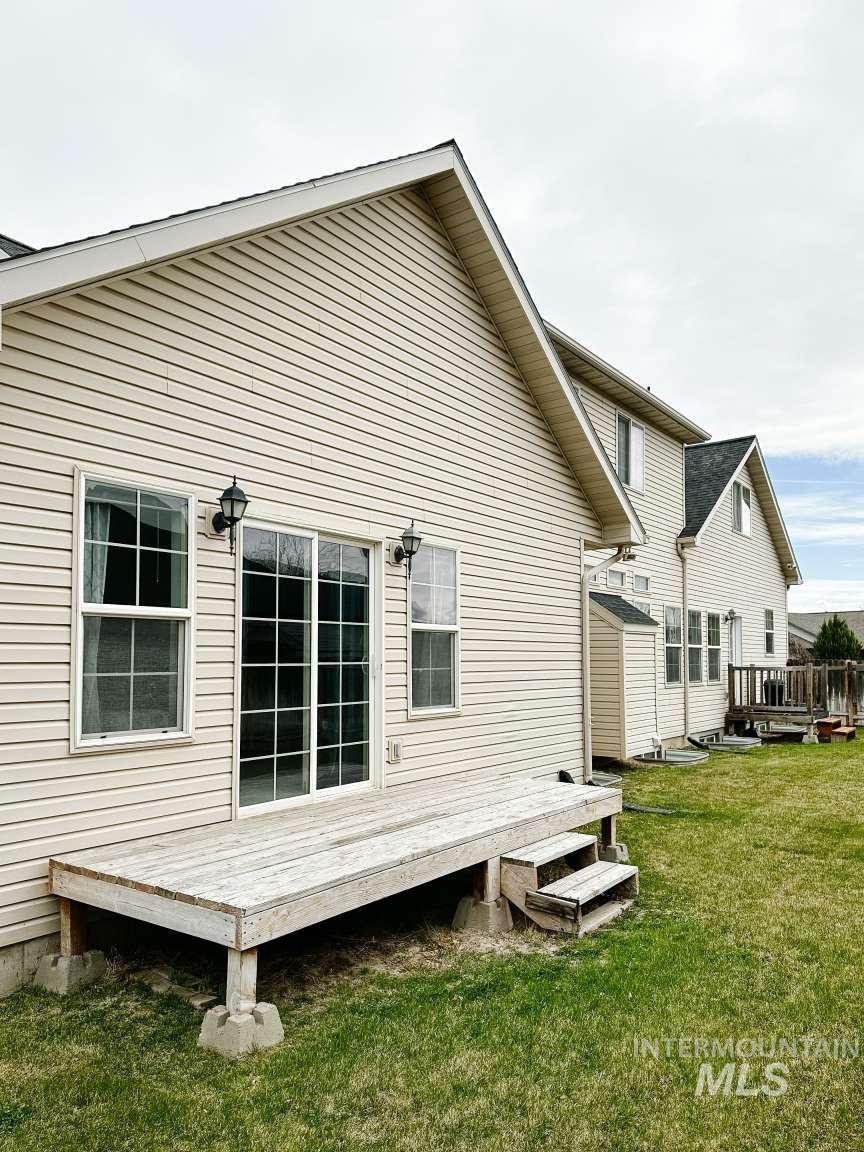 Back of house with a wooden deck and a yard