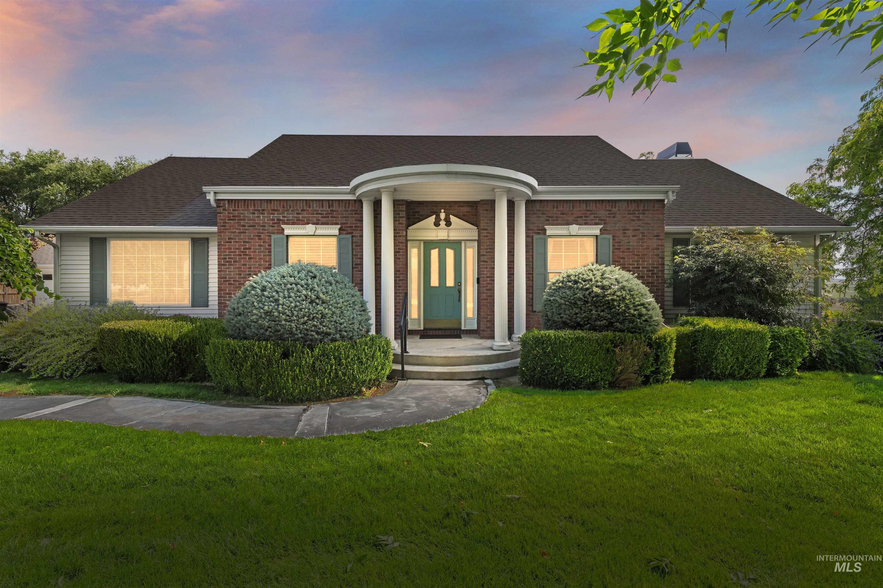 Greek revival house with roof with shingles, brick siding, and a front yard