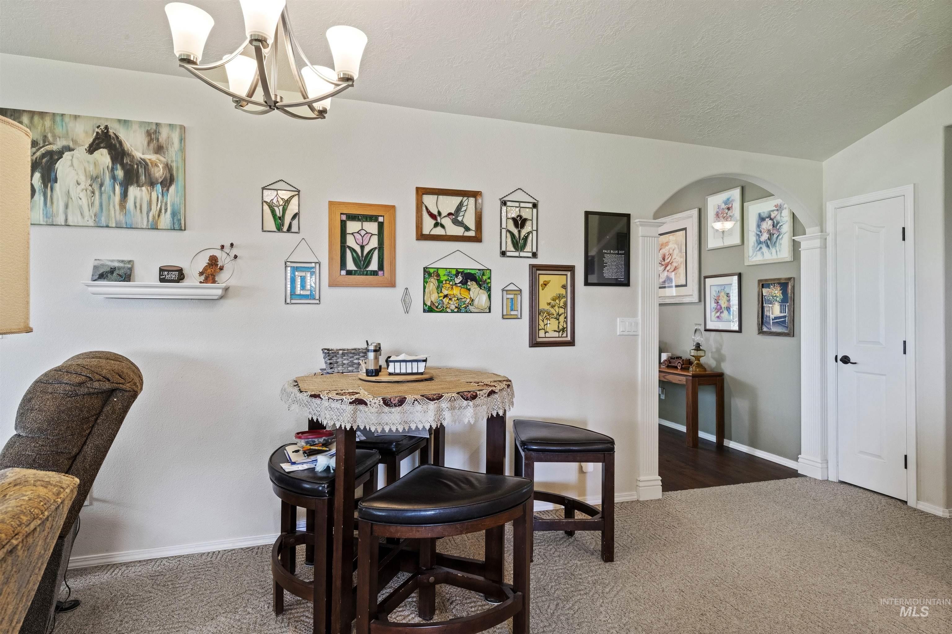 Dining area featuring dark colored carpet, a chandelier, a textured ceiling, and arched walkways