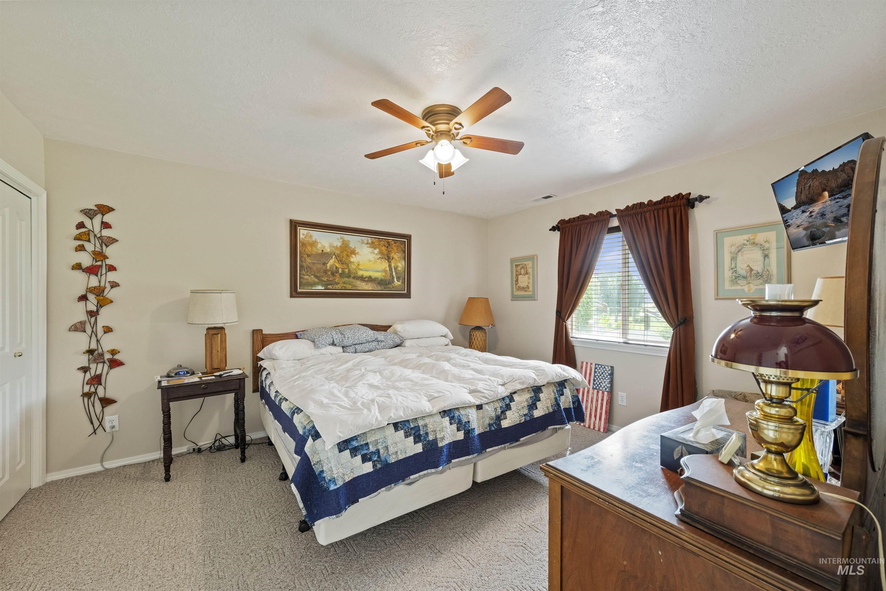 Bedroom featuring carpet flooring, a ceiling fan, and a textured ceiling