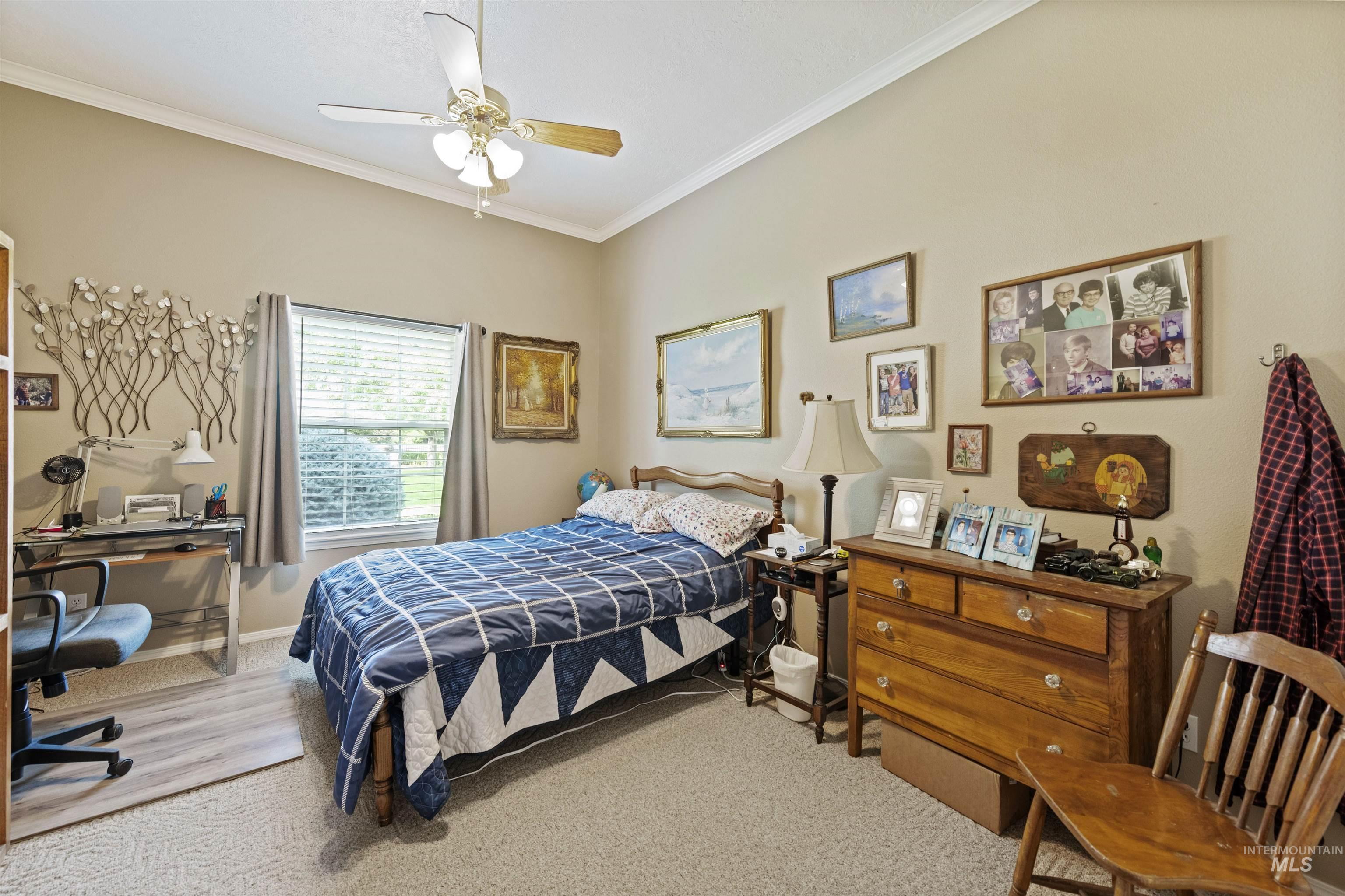 Bedroom featuring a desk, ornamental molding, carpet, and a ceiling fan