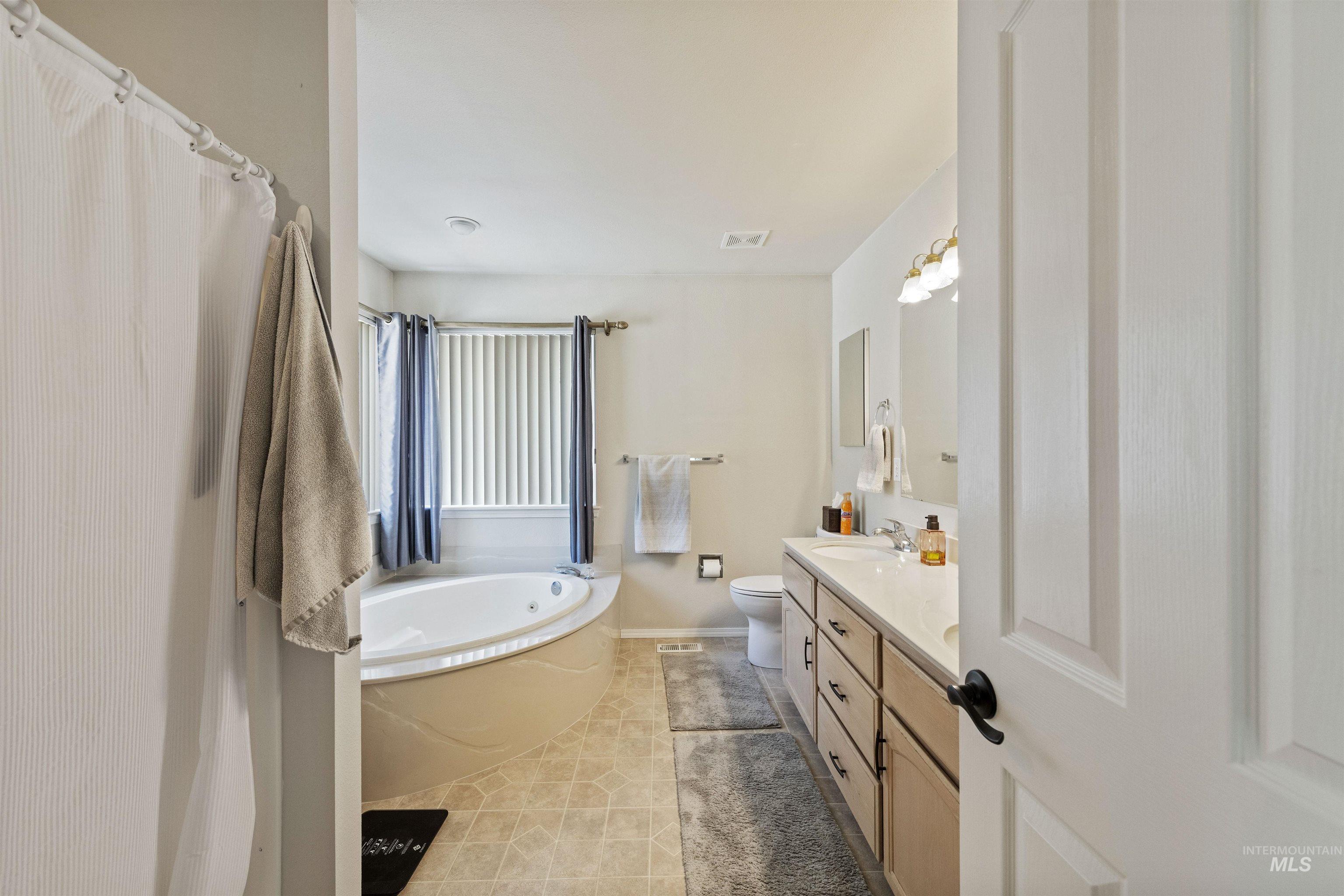 Bathroom featuring a garden tub, vanity, and light tile patterned floors