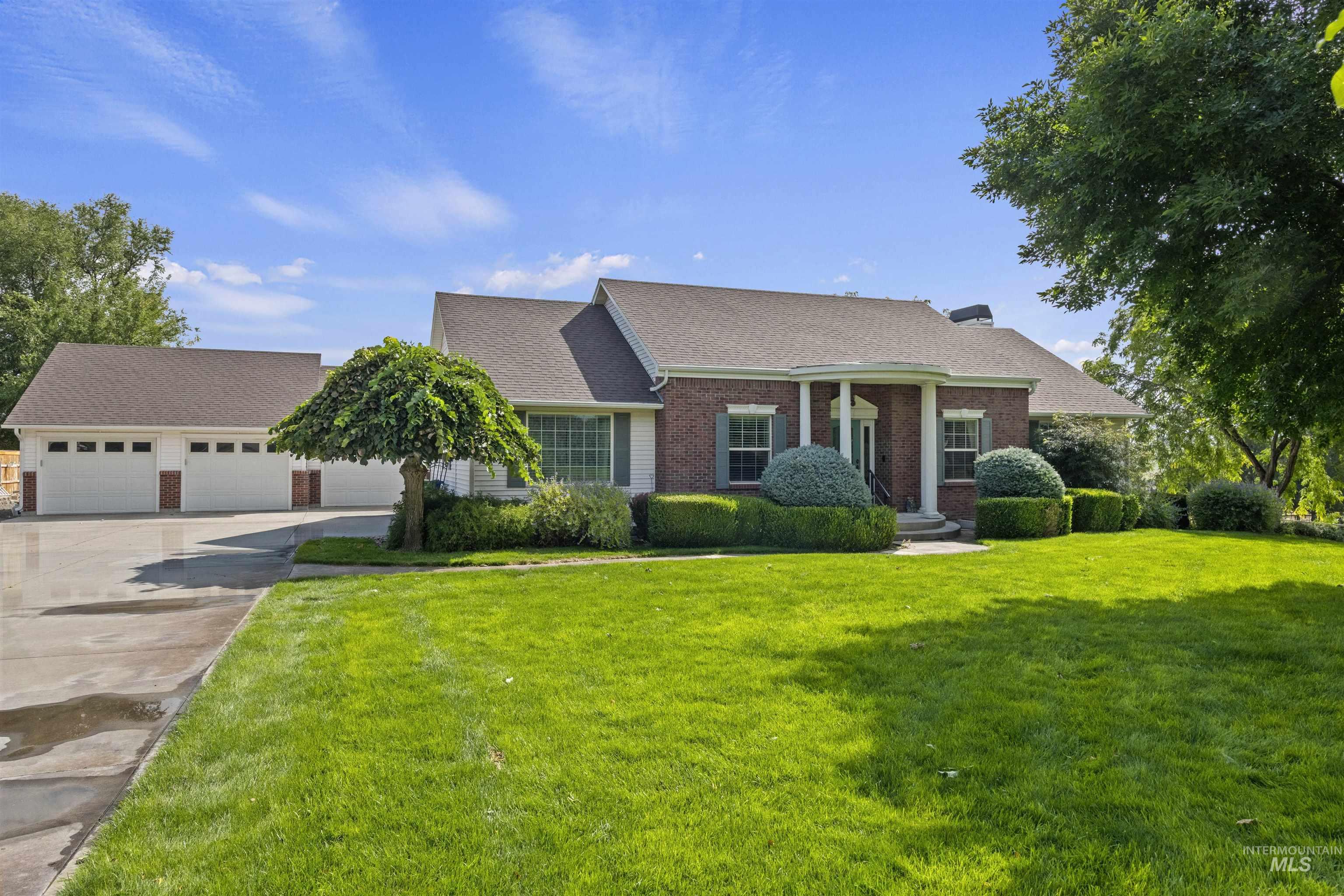 View of front of home with roof with shingles, brick siding, a front lawn, covered porch, and driveway