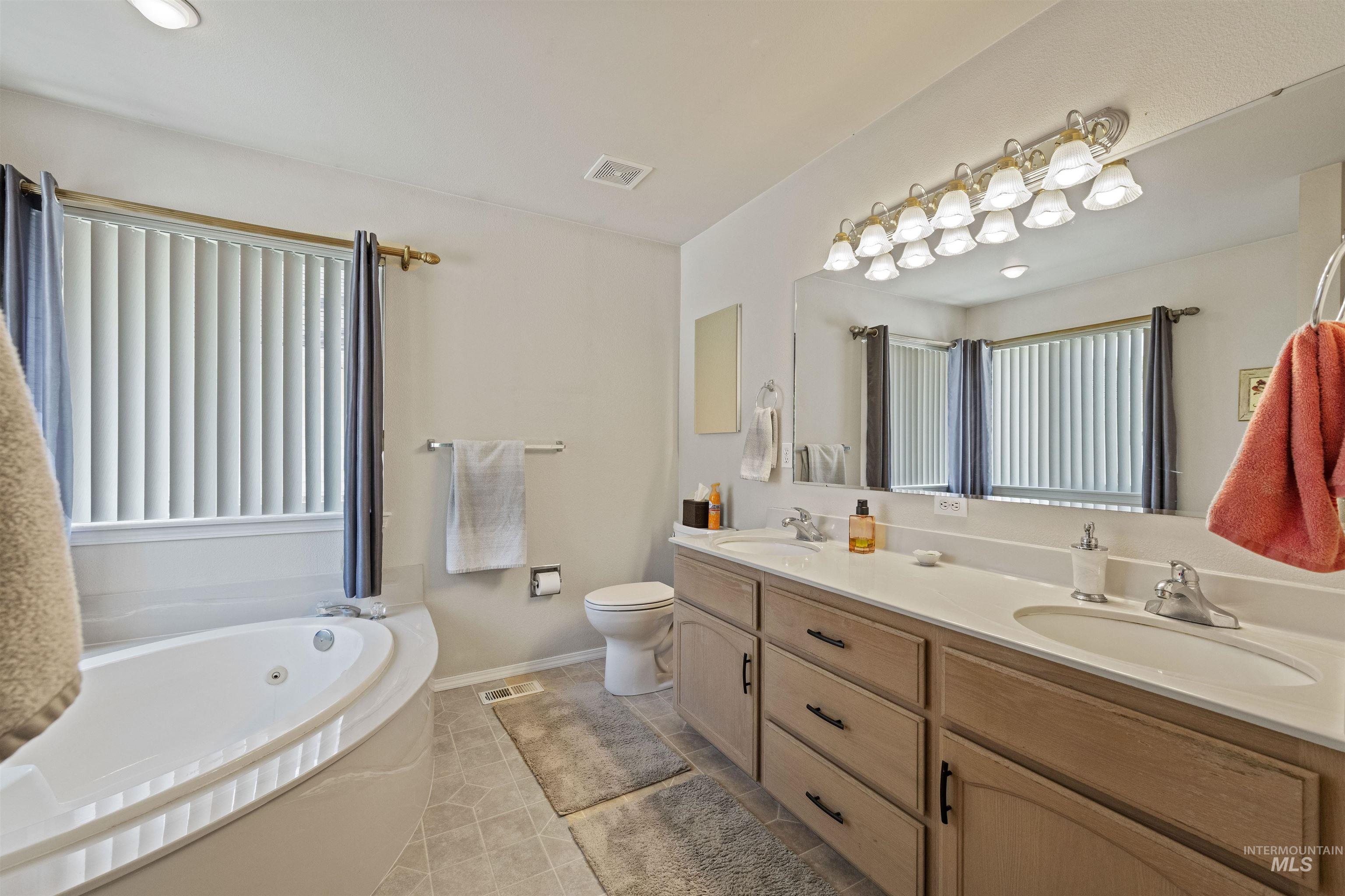 Bathroom featuring a whirlpool tub, double vanity, and light tile patterned flooring