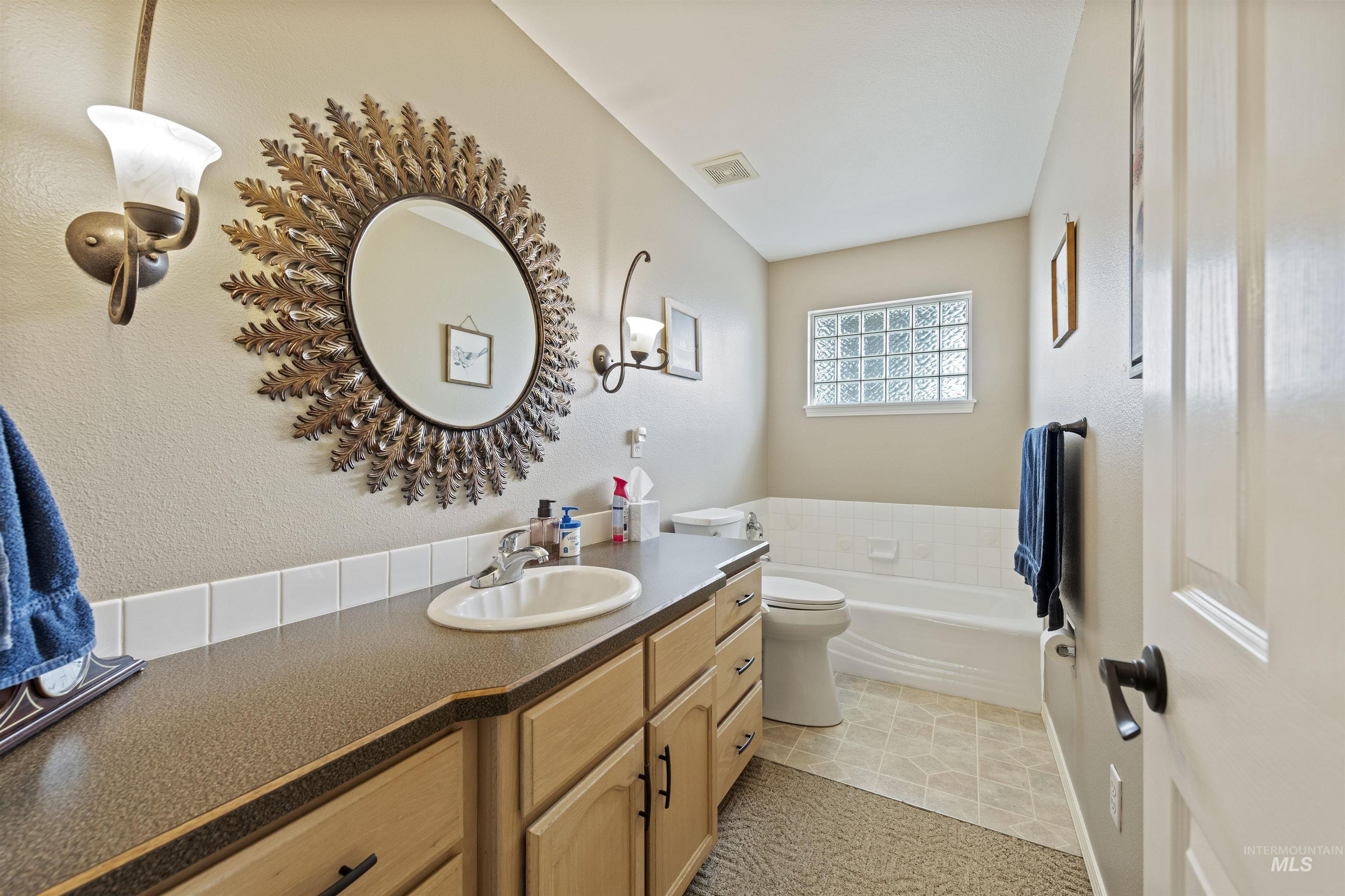 Full bathroom featuring a garden tub, vanity, a textured wall, and light tile patterned floors