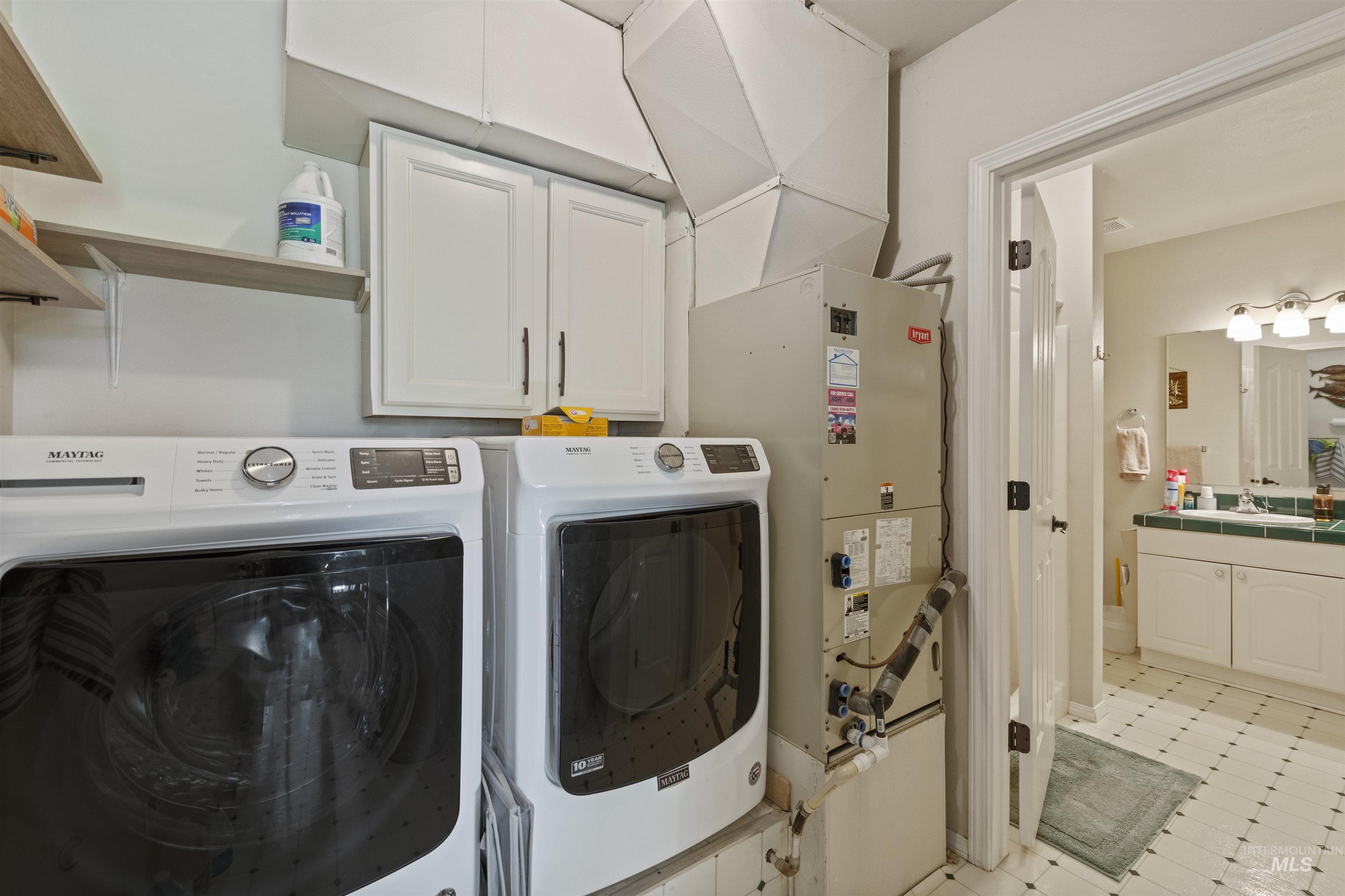 Laundry room with cabinet space, washer and dryer, and heating unit