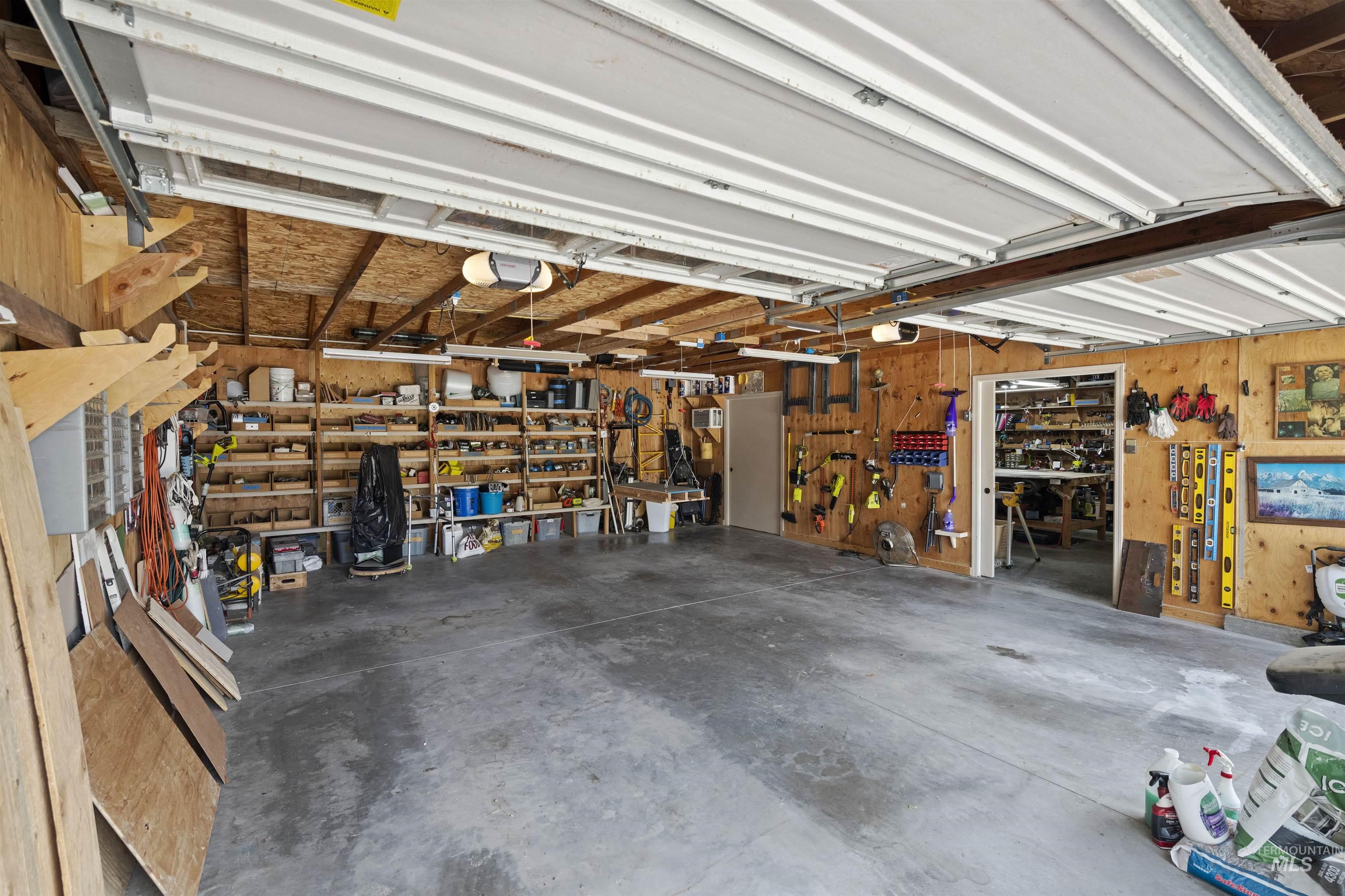 Garage featuring a workshop area, wood walls, and a garage door opener