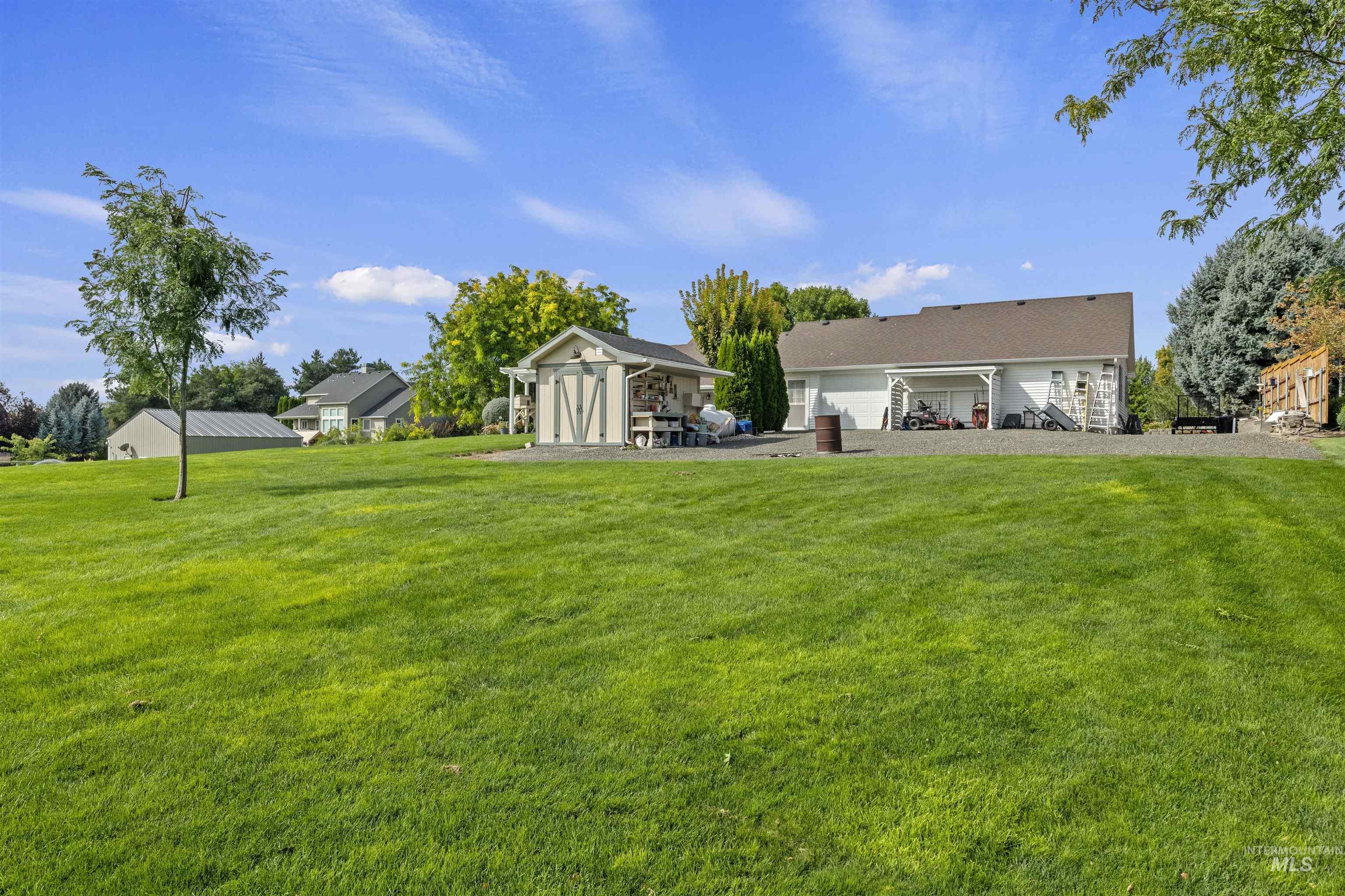 View of green lawn with a garage and a patio area