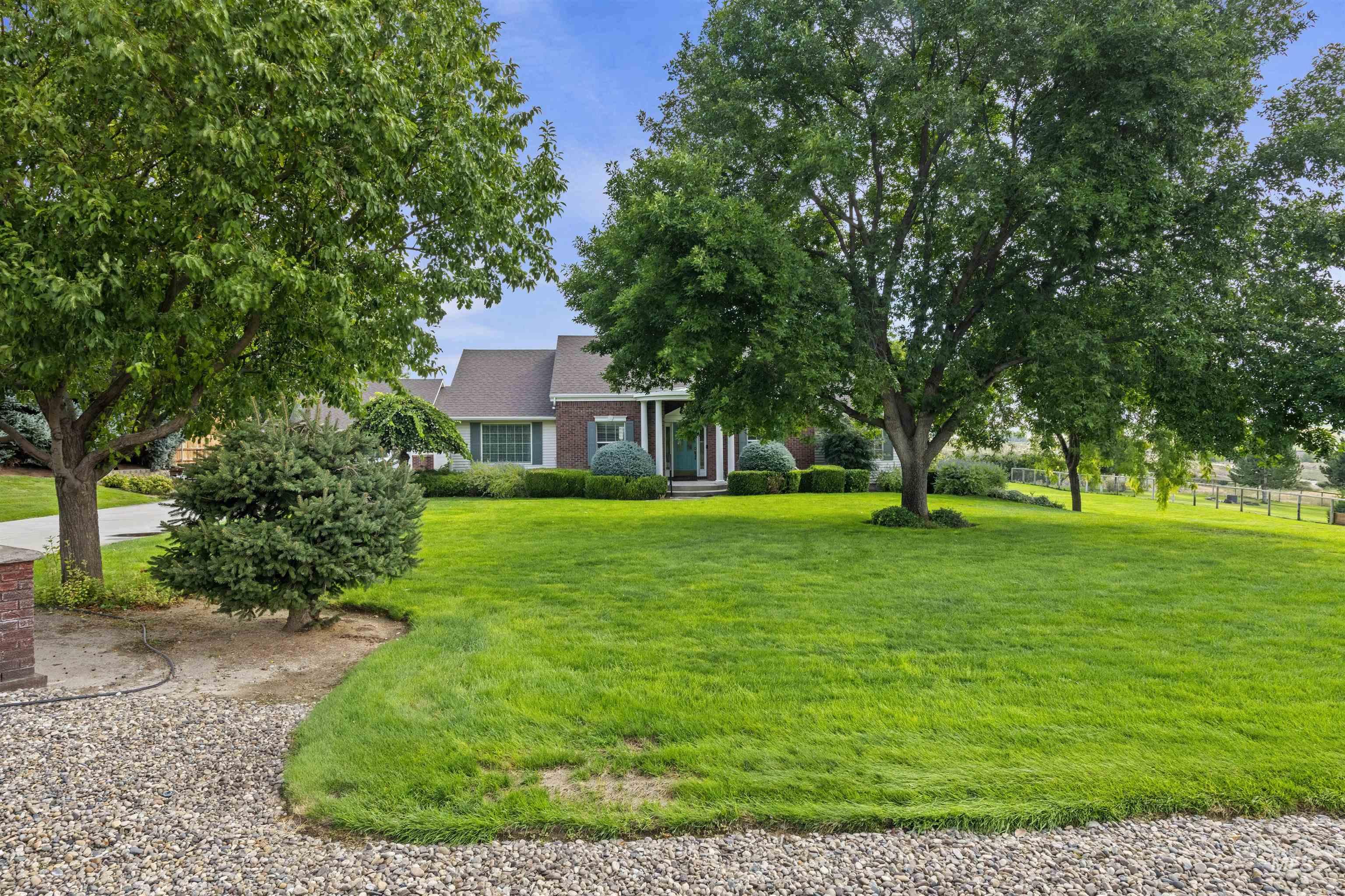 View of property hidden behind natural elements with a front lawn and brick siding