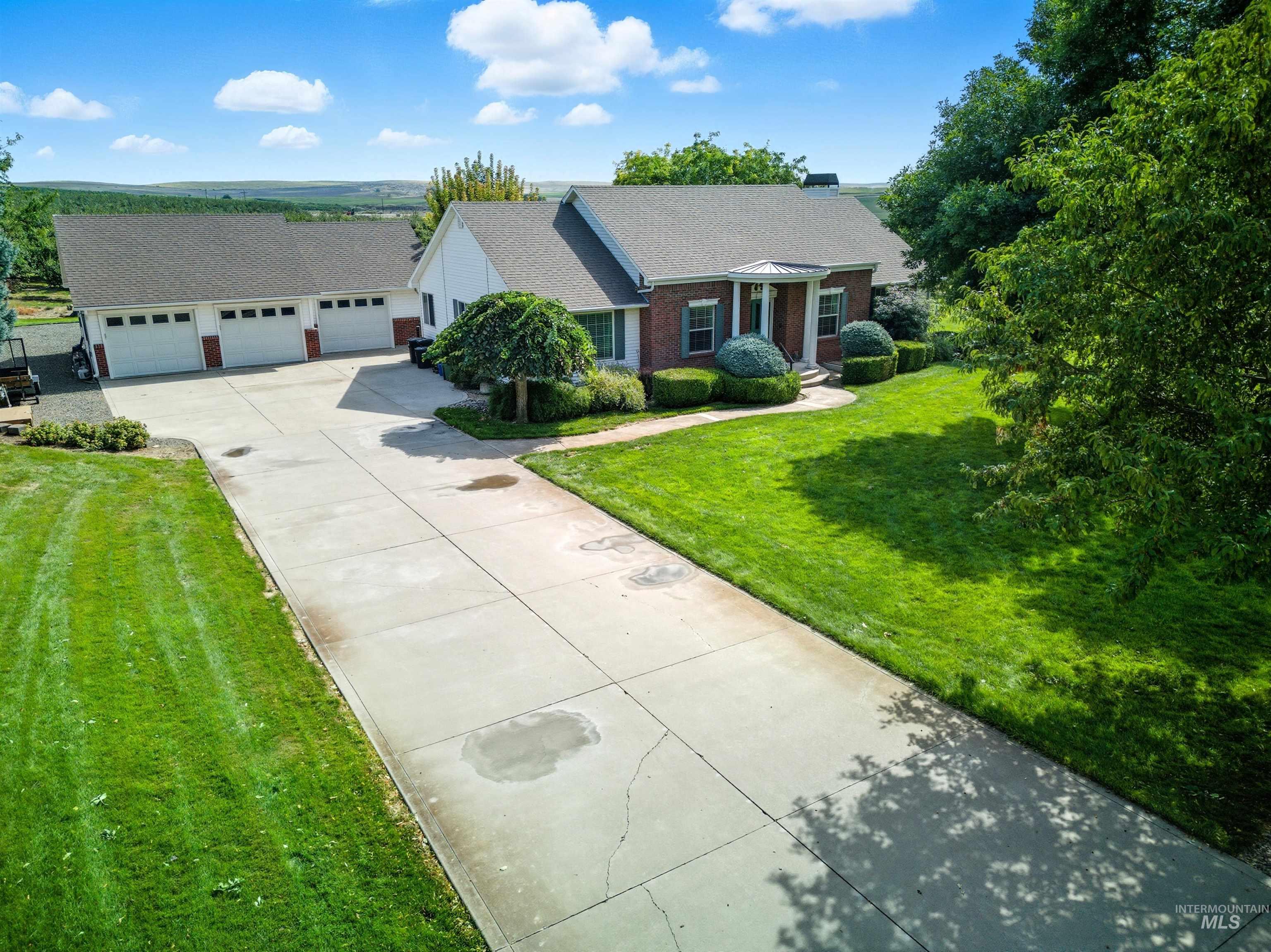 View of front of home with driveway, a front lawn, brick siding, and roof with shingles