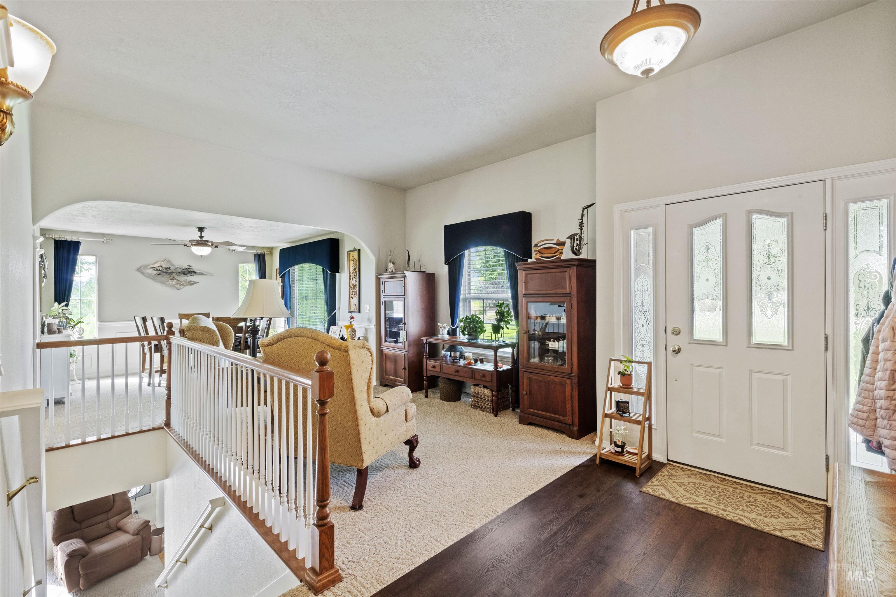 Entryway featuring arched walkways, a ceiling fan, wood finished floors, and carpet floors