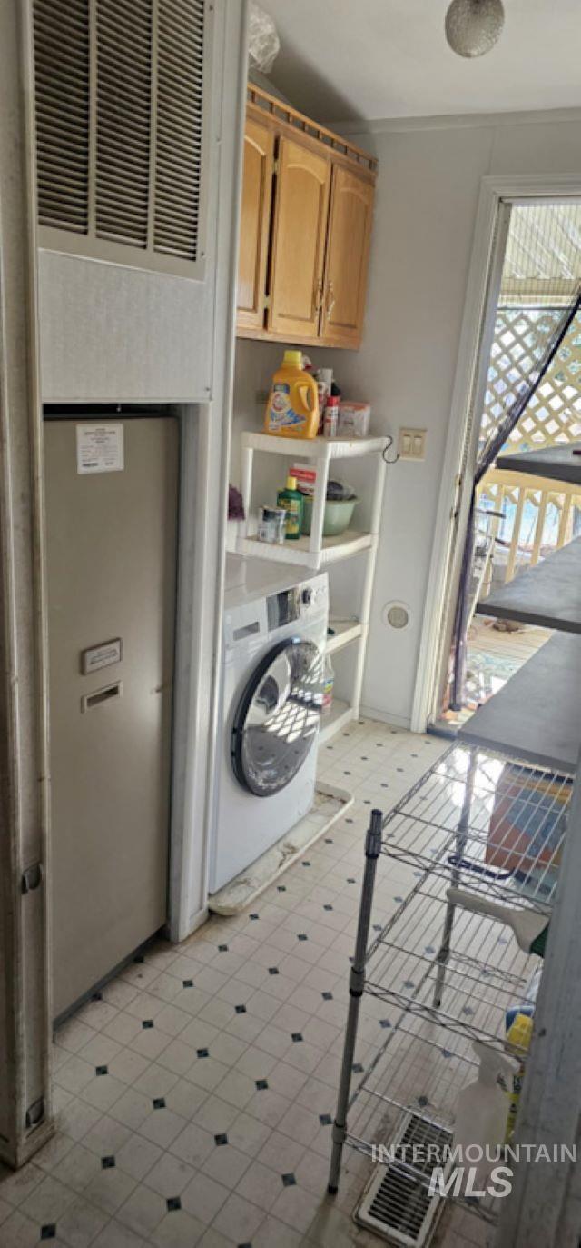Washroom featuring cabinet space, a heating unit, light flooring, and washer / clothes dryer