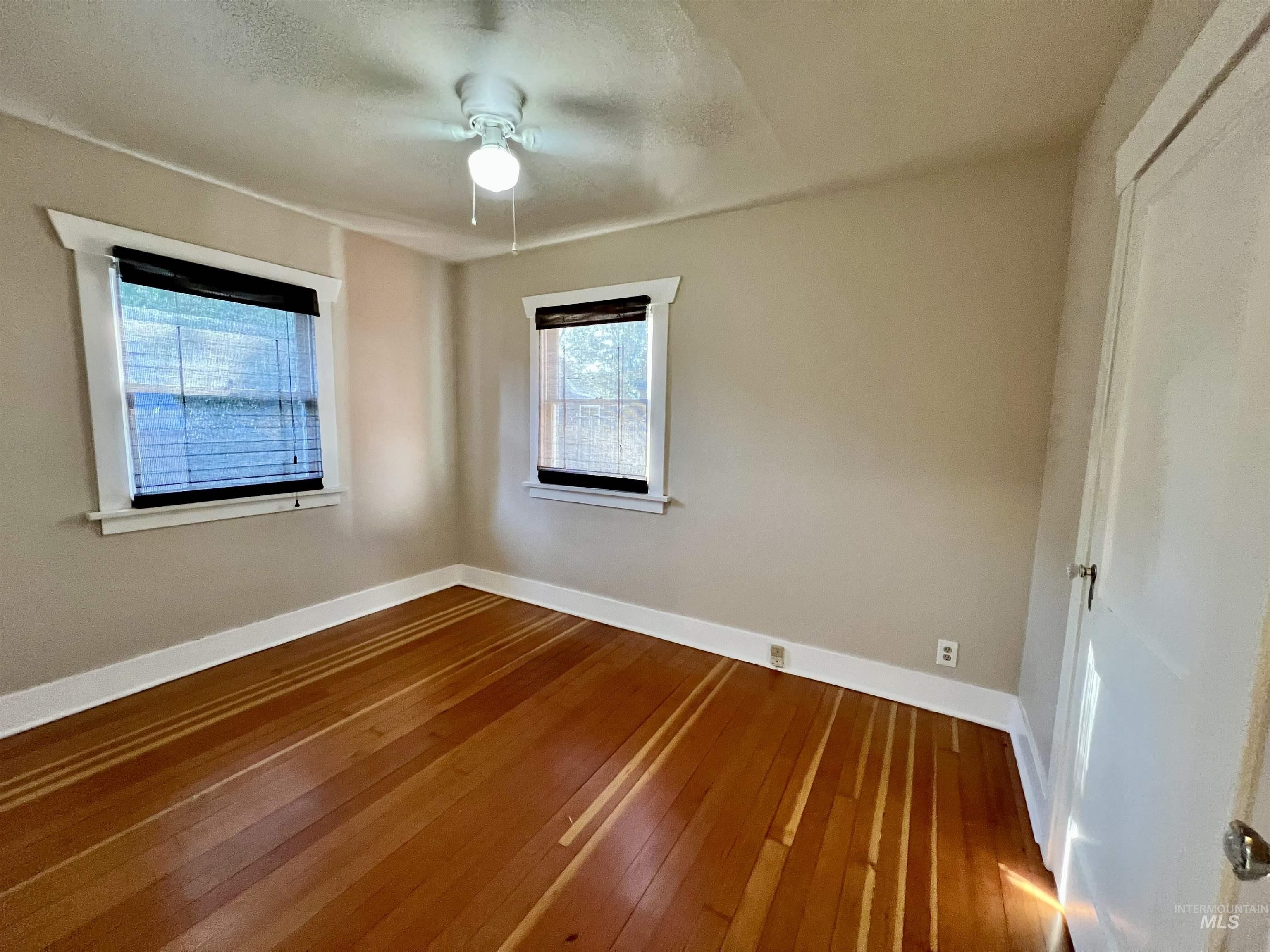 Spare room with dark wood finished floors and a ceiling fan
