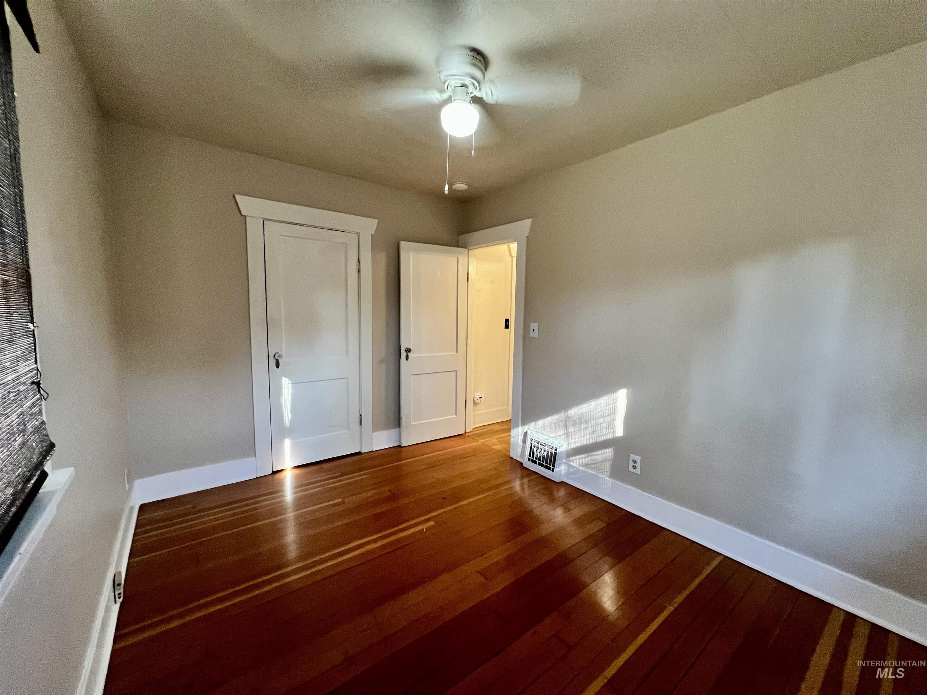 Unfurnished bedroom featuring hardwood / wood-style floors, ceiling fan, and a closet