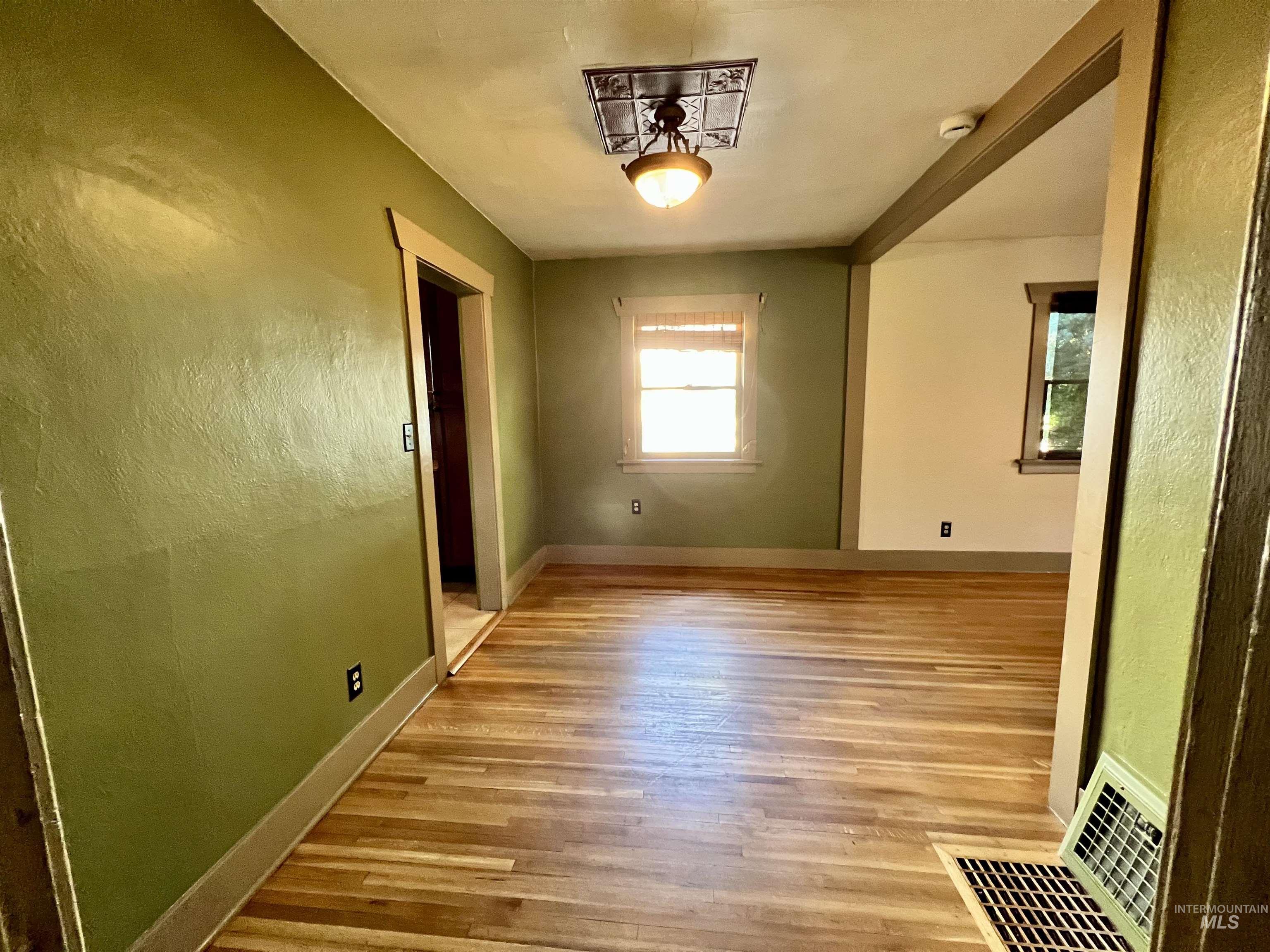 Unfurnished room with a textured wall and light wood-type flooring