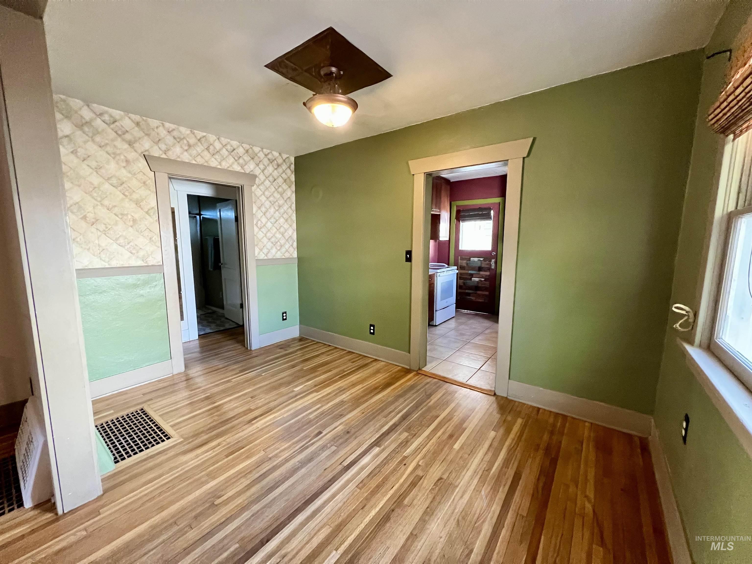 Unfurnished bedroom featuring light wood-style flooring and wallpapered walls