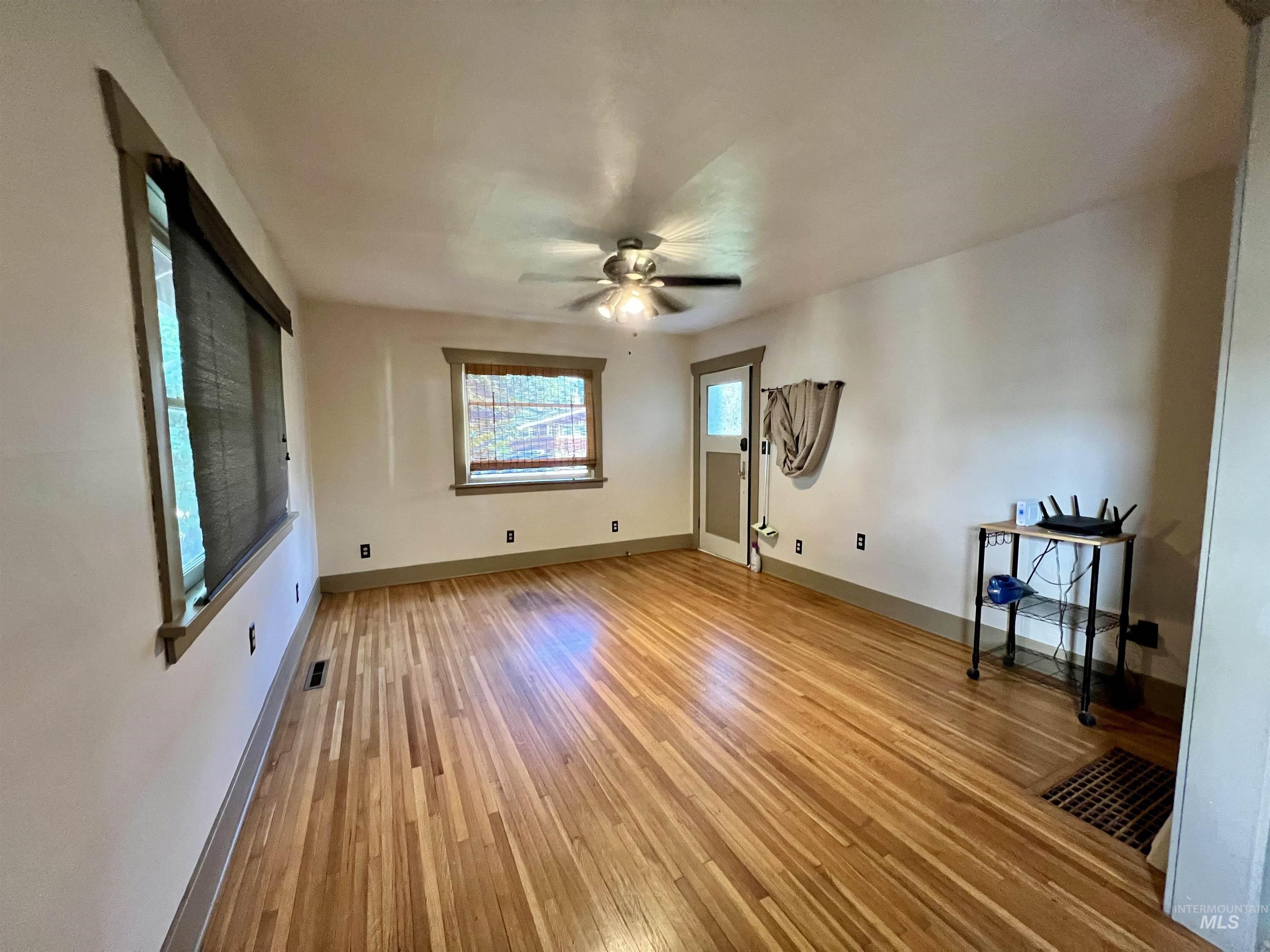 Unfurnished living room with light wood-style floors and a ceiling fan