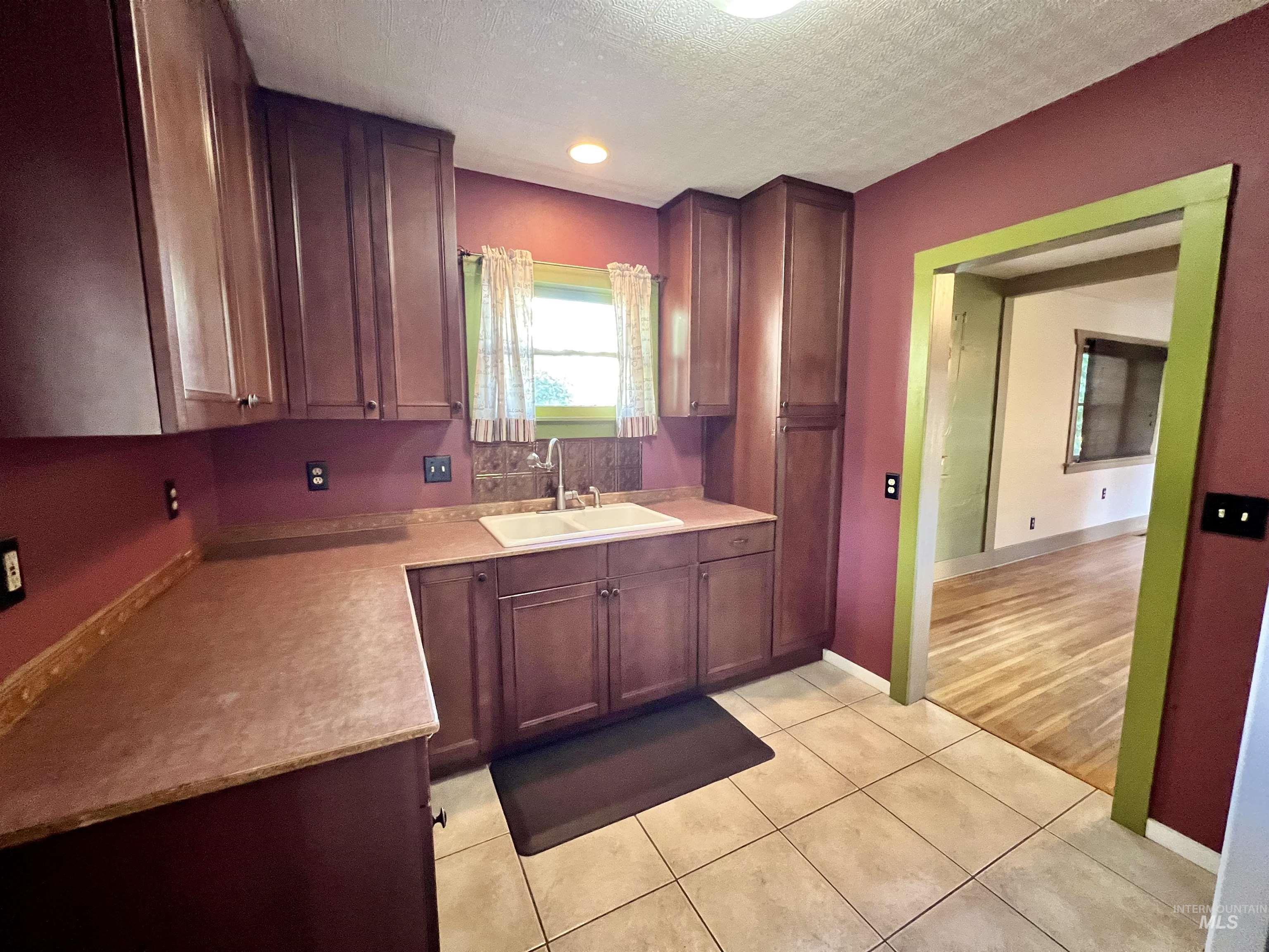 Kitchen with light countertops, a textured ceiling, and light tile patterned floors