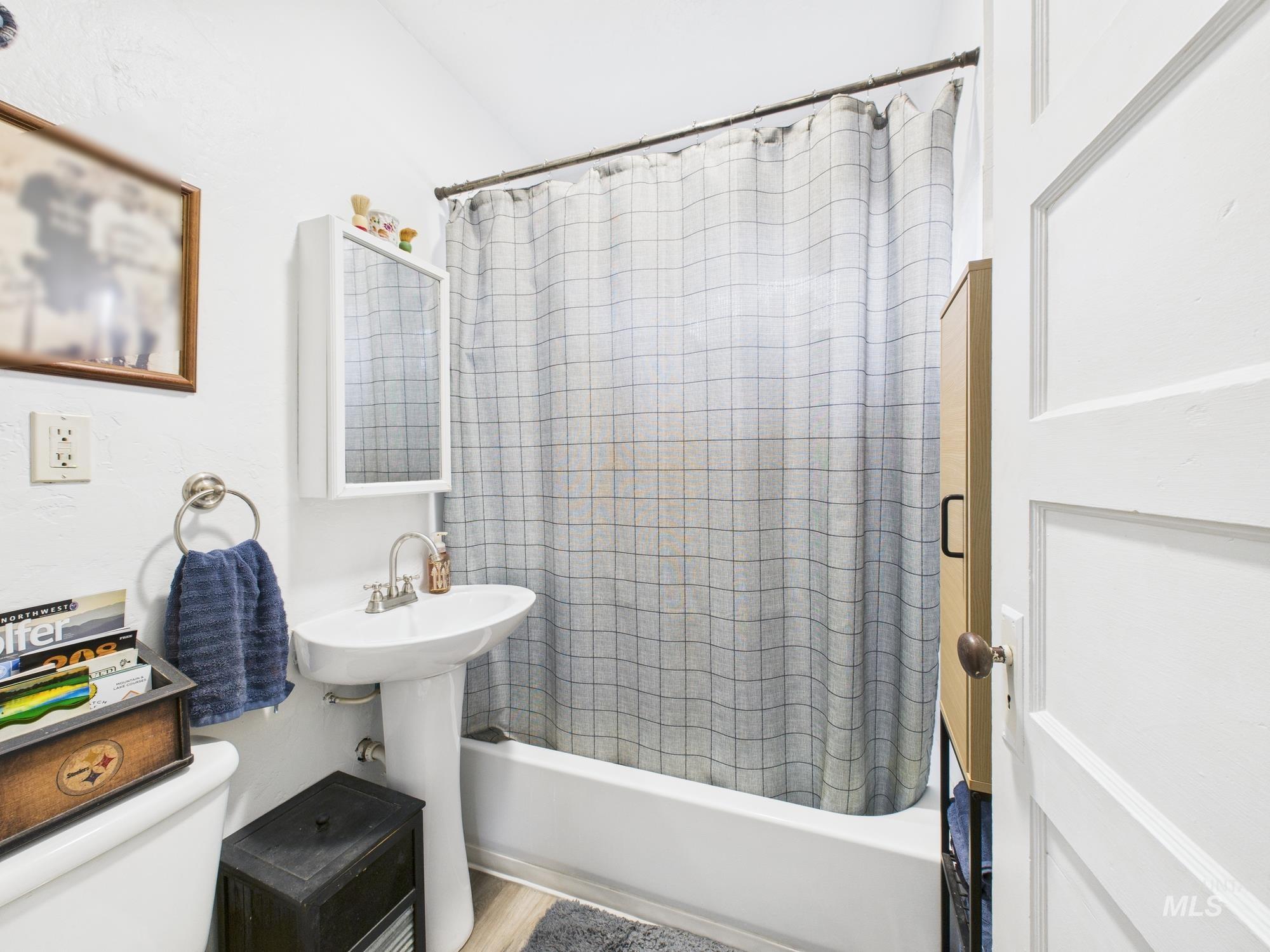 Bathroom featuring shower / bathtub combination with curtain and toilet