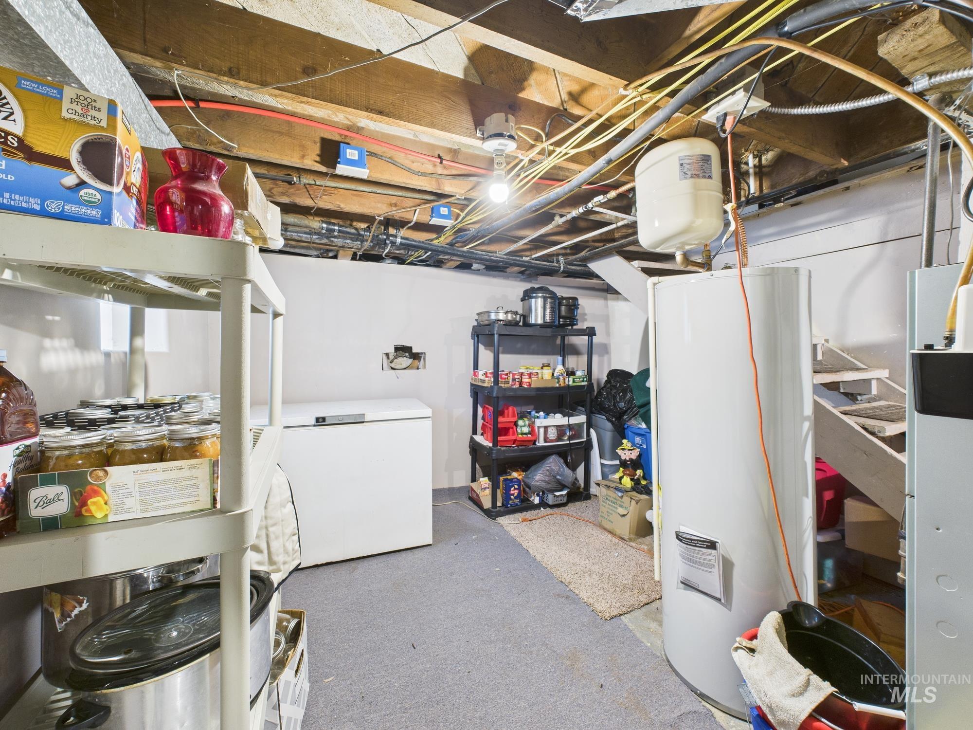 Unfinished basement with water heater and white fridge