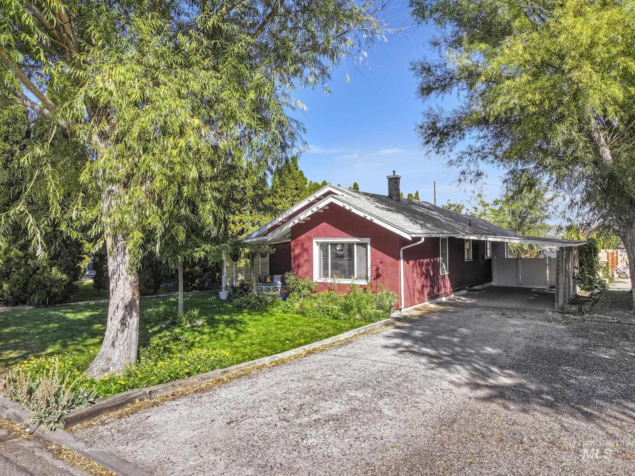 View of front facade with an attached carport, driveway, a front yard, and a chimney