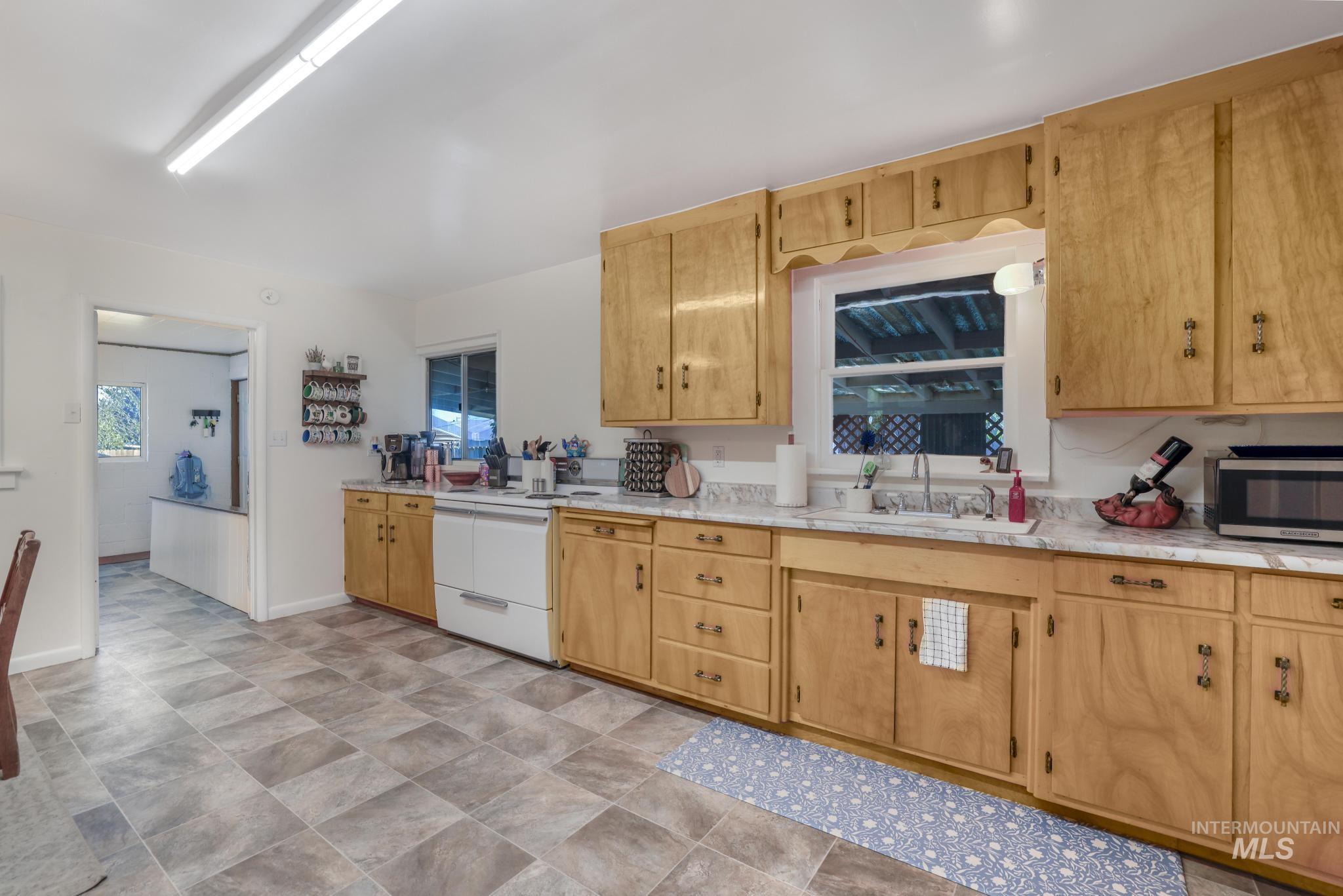 Kitchen featuring light countertops, white electric range, stainless steel microwave, and open shelves