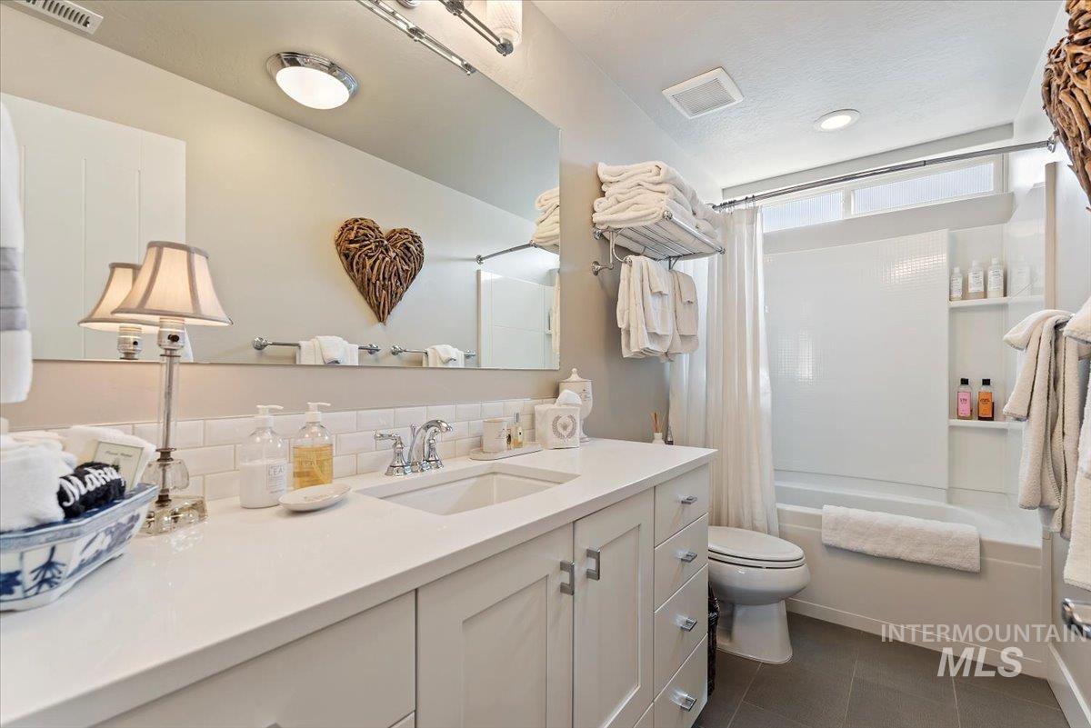 Bathroom with shower / bath combination with curtain, vanity, and dark tile patterned flooring