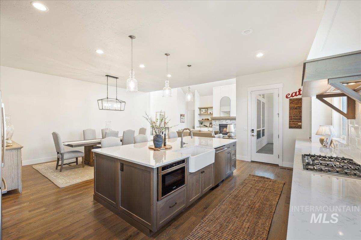 Kitchen featuring appliances with stainless steel finishes, recessed lighting, dark wood finished floors, dark brown cabinets, and an island with sink