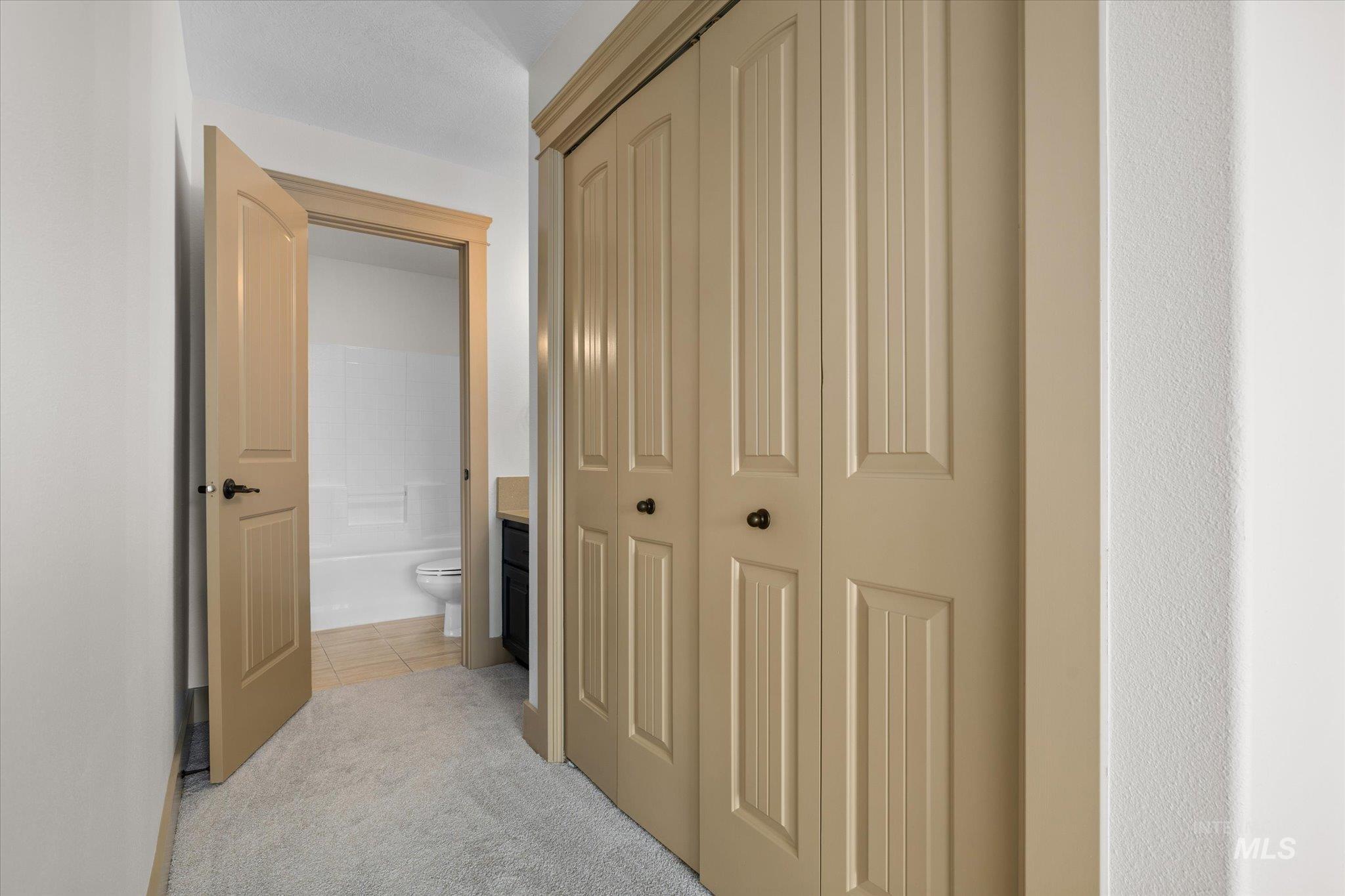 Hallway featuring light tile patterned floors and light colored carpet